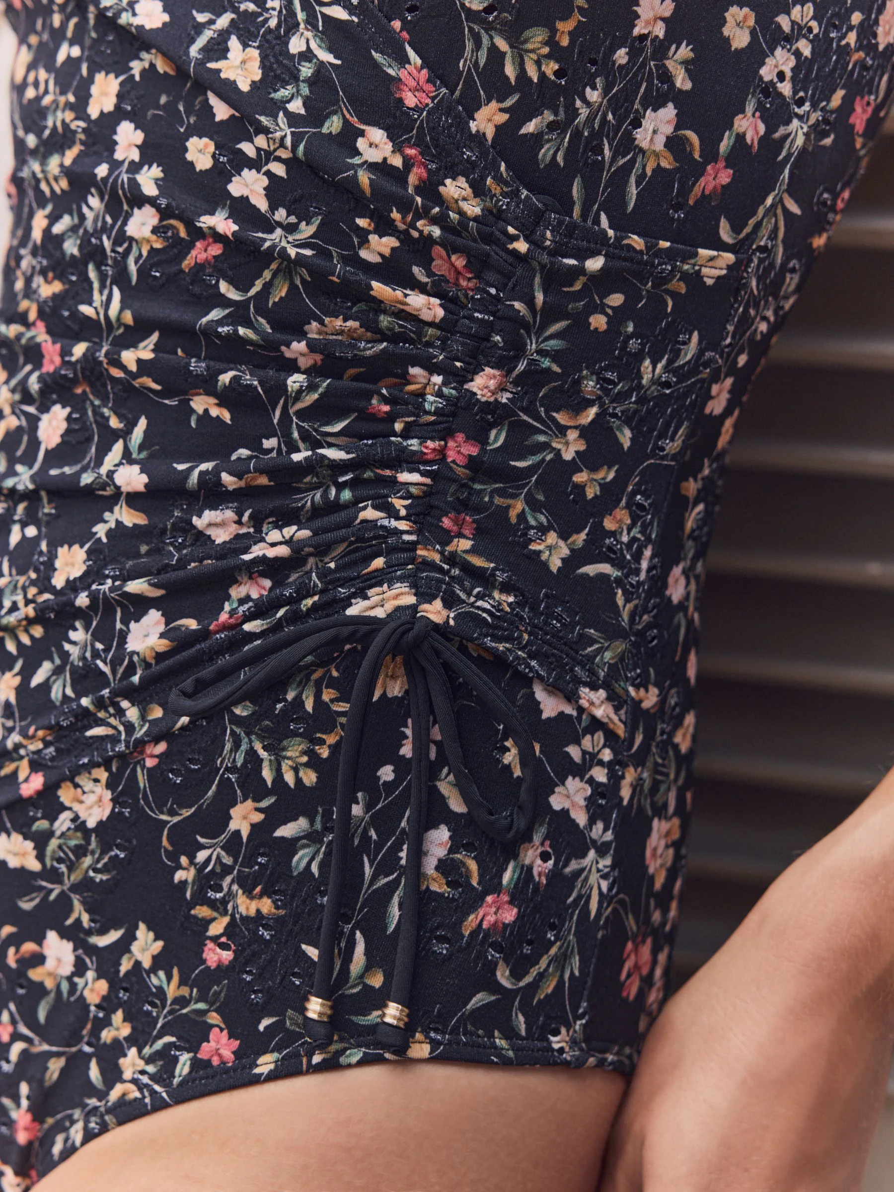 Zwart met broderie en fijne print - Badpak met vormgevende zijrimpeling en buikcorrectie