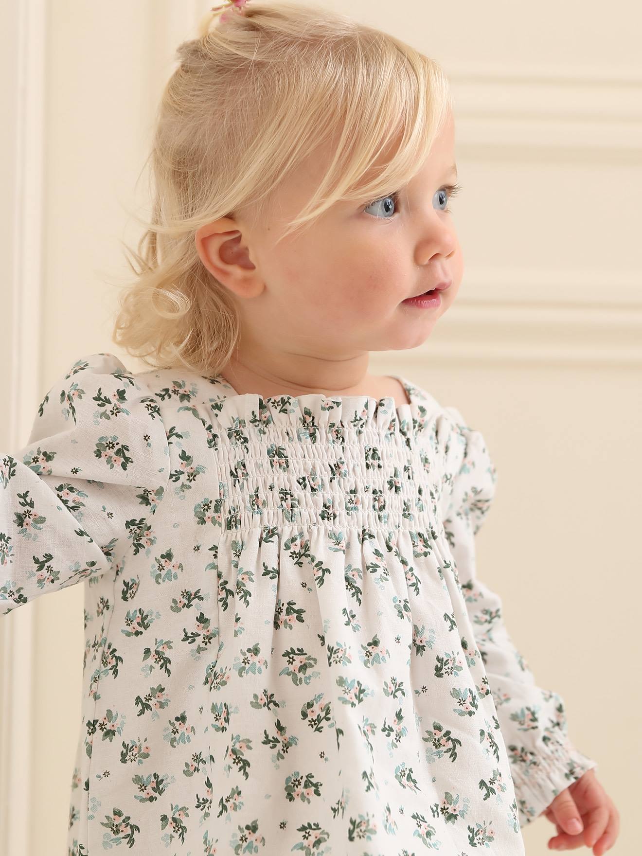 Vestido floral branco para bebê com detalhes franzidos.