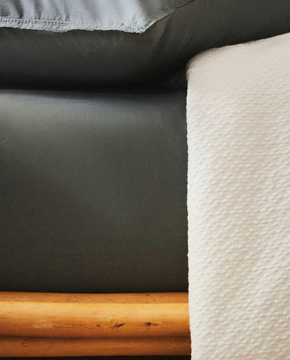 Lençol de algodão infantil com elástico e costura decorativa.