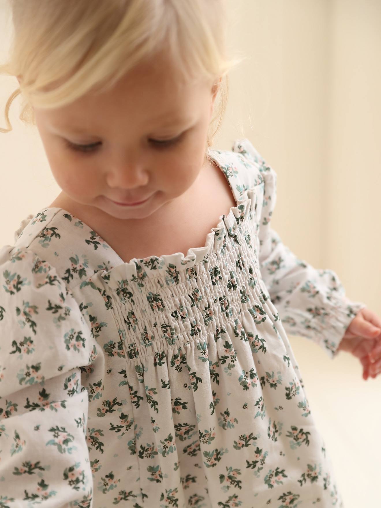 Vestido floral branco para bebê com detalhes franzidos.