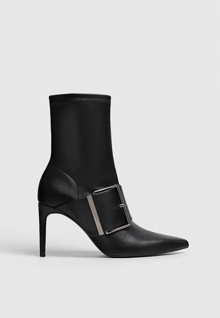 Botas pretas de cano curto com salto alto e fivelas.