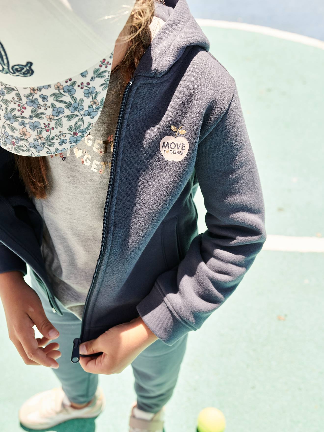 Moletom infantil feminino azul médio liso com zíper, capuz esportivo e detalhes decorativos.