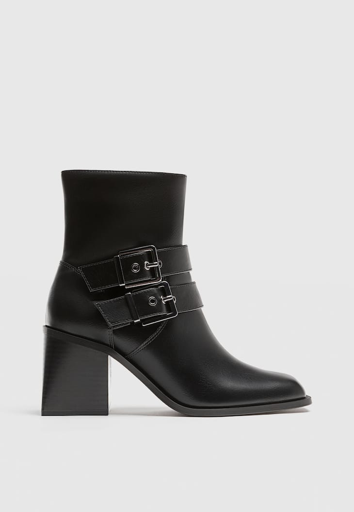 Botas pretas de cano curto com salto alto e fivelas.