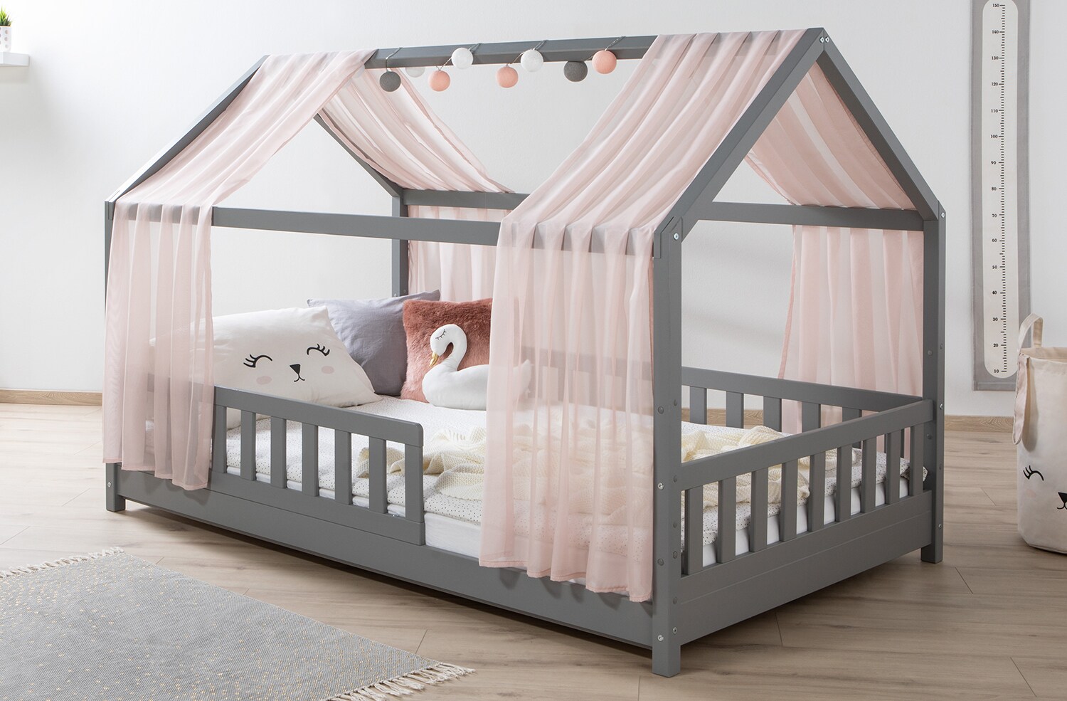 TiCAA Hausbett mit Tüll Kim 90x200 cm, 100x200 cm, 120x200 cm, 140x200 für Jungen & Mädchen, inkl. Rolllattenrost, Rausfallschutz variabel, Montessori Bett Hellgrau aus Kiefer Massivholz