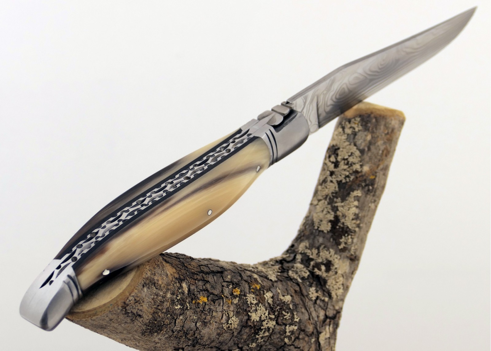 Couteau Laguiole prestige avec un manche en pointe de corne blonde et mitres en acier inoxydable et lame Damas