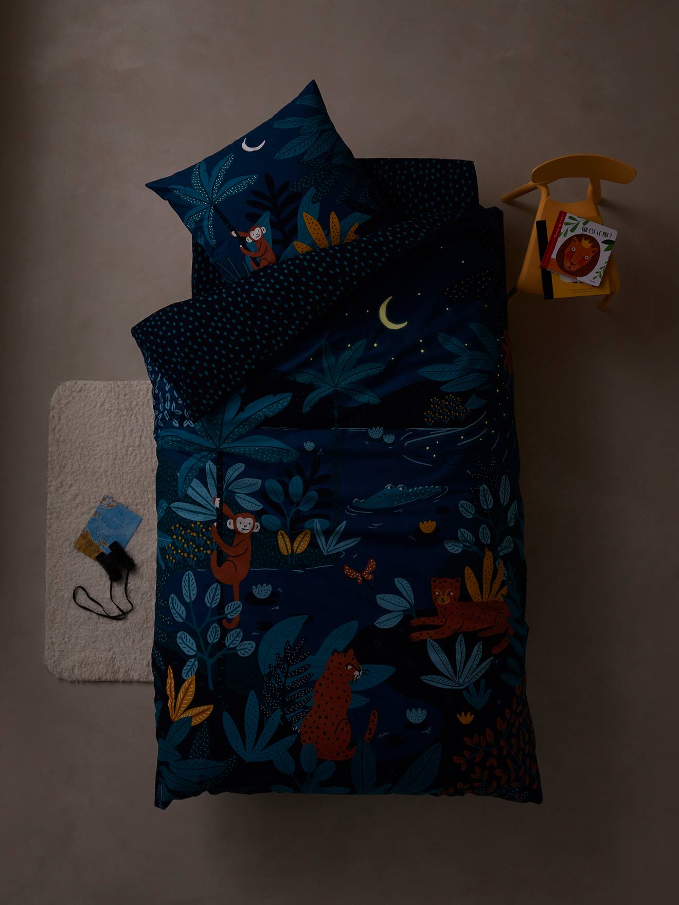Conjunto infantil Jungle Night com capa de edredom e fronha, azul escuro liso com estampas.
