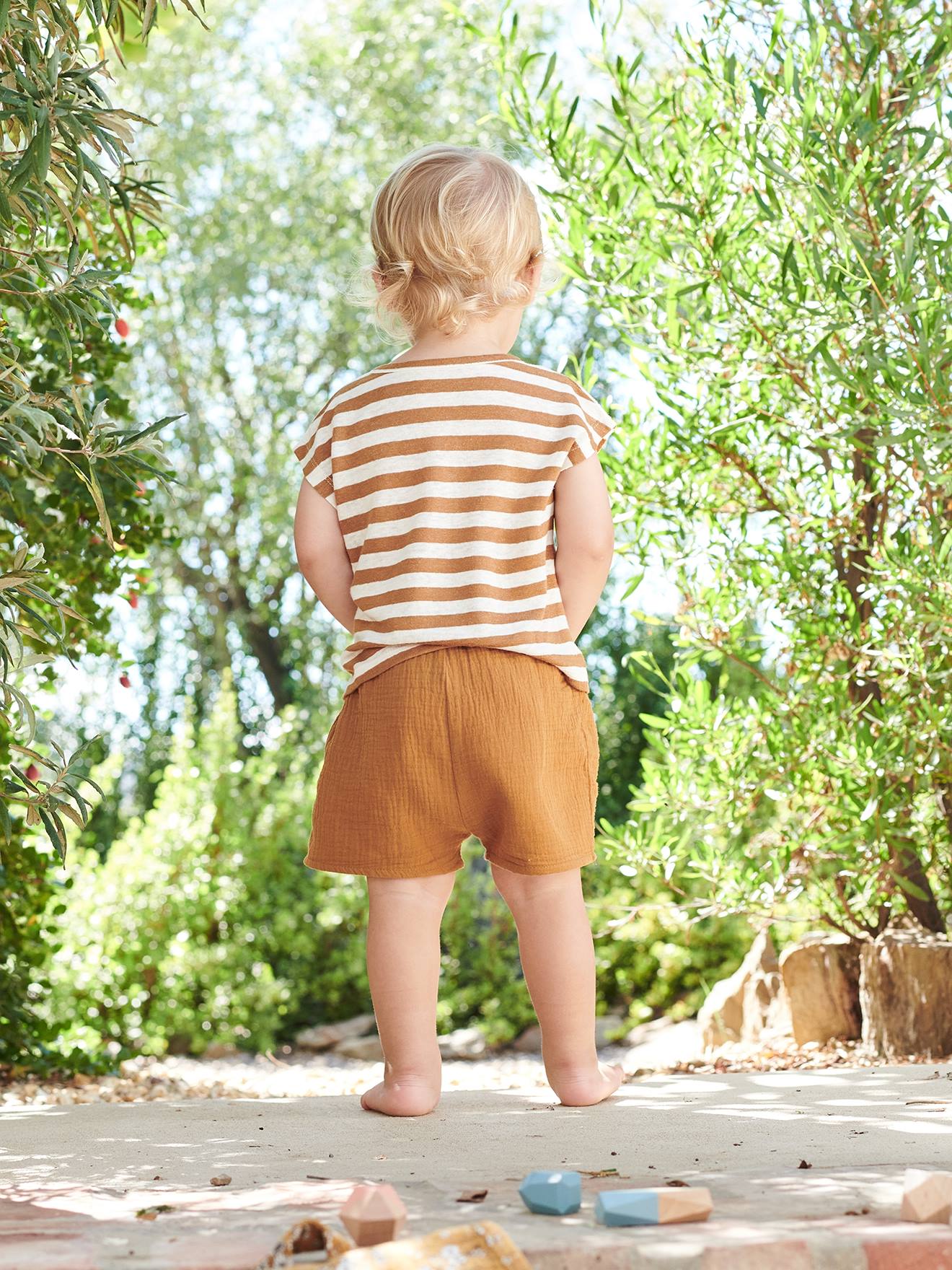 Roupa de bebê: camiseta listrada e shorts azul-claro liso.