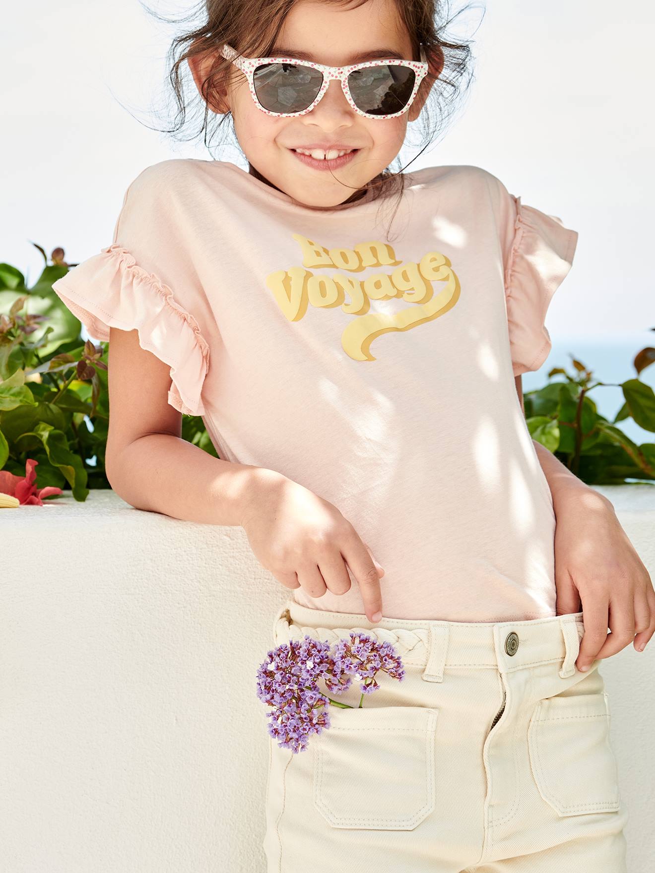 Camiseta infantil rosa claro com mensagem em relevo e mangas curtas com babados.
