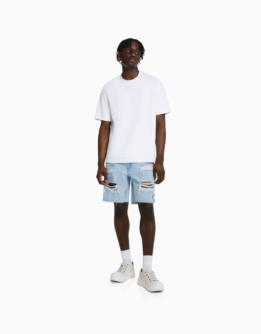 Bermuda jeans rasgada com respingos de tinta