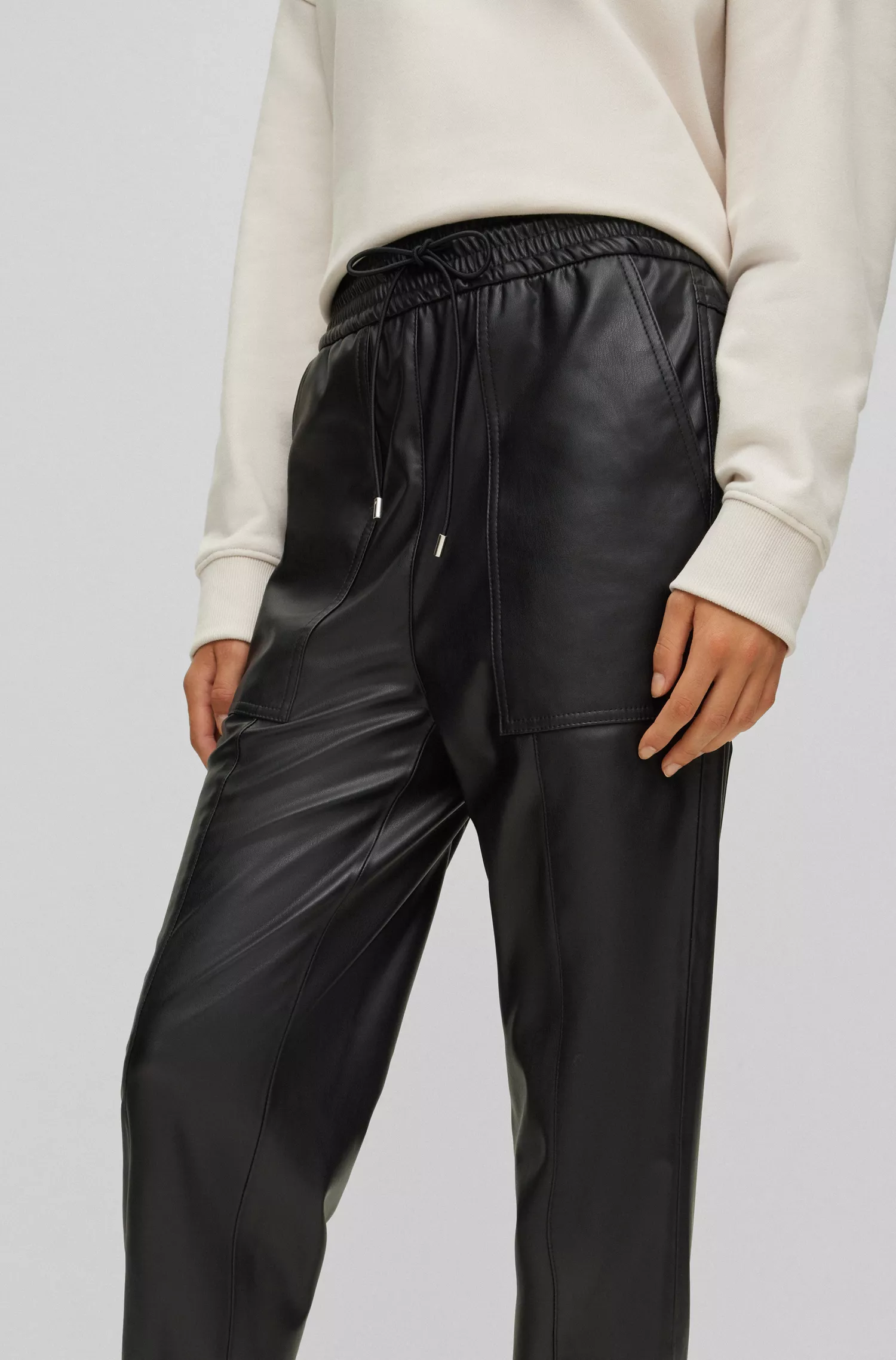 Calça BOSS laranja, corte relaxado, em tecido revestido, com cintura ajustável por cordão.