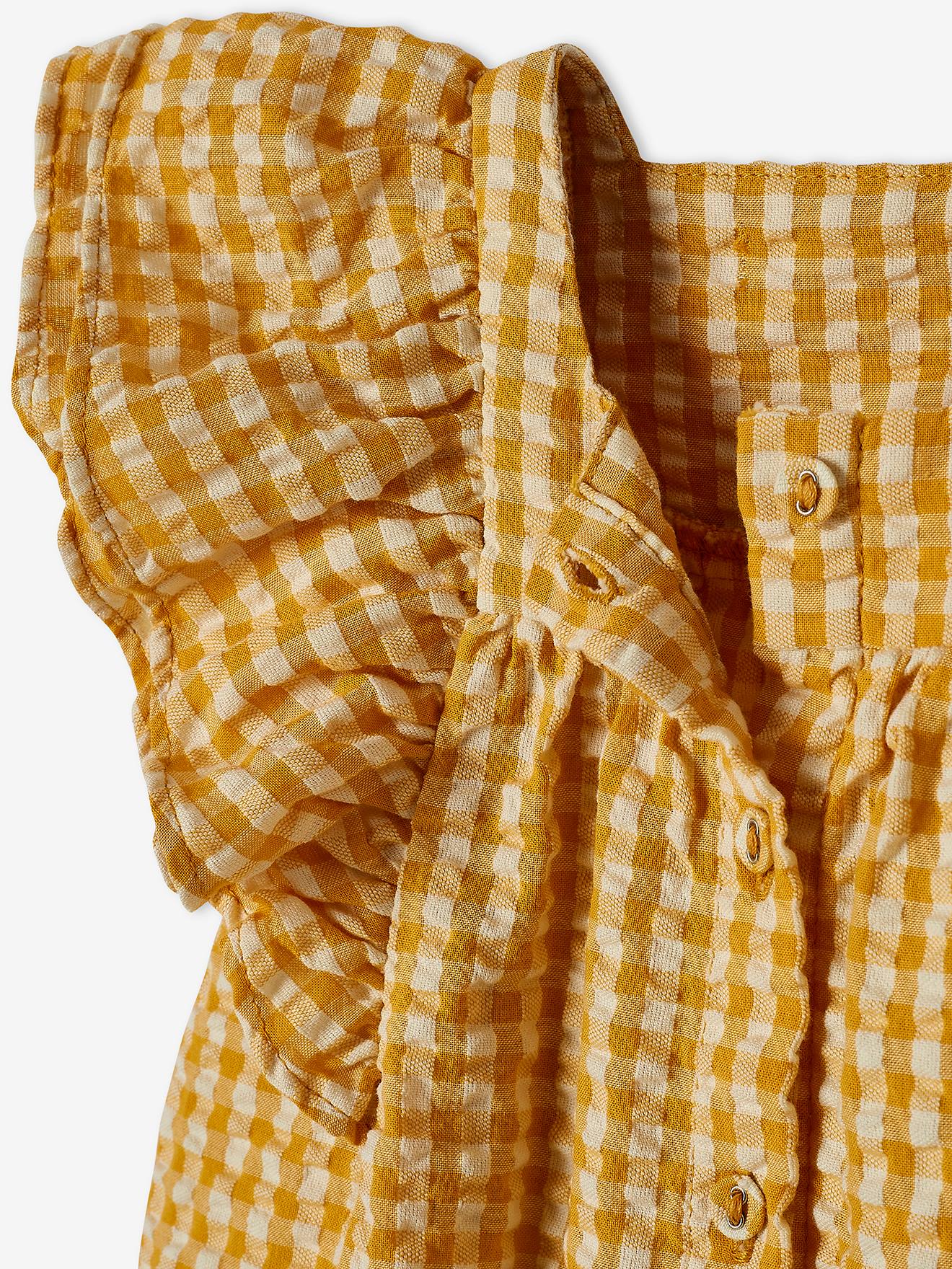 Conjunto infantil tamanho médio com blusa xadrez amarela e calça jeans de pernas largas.