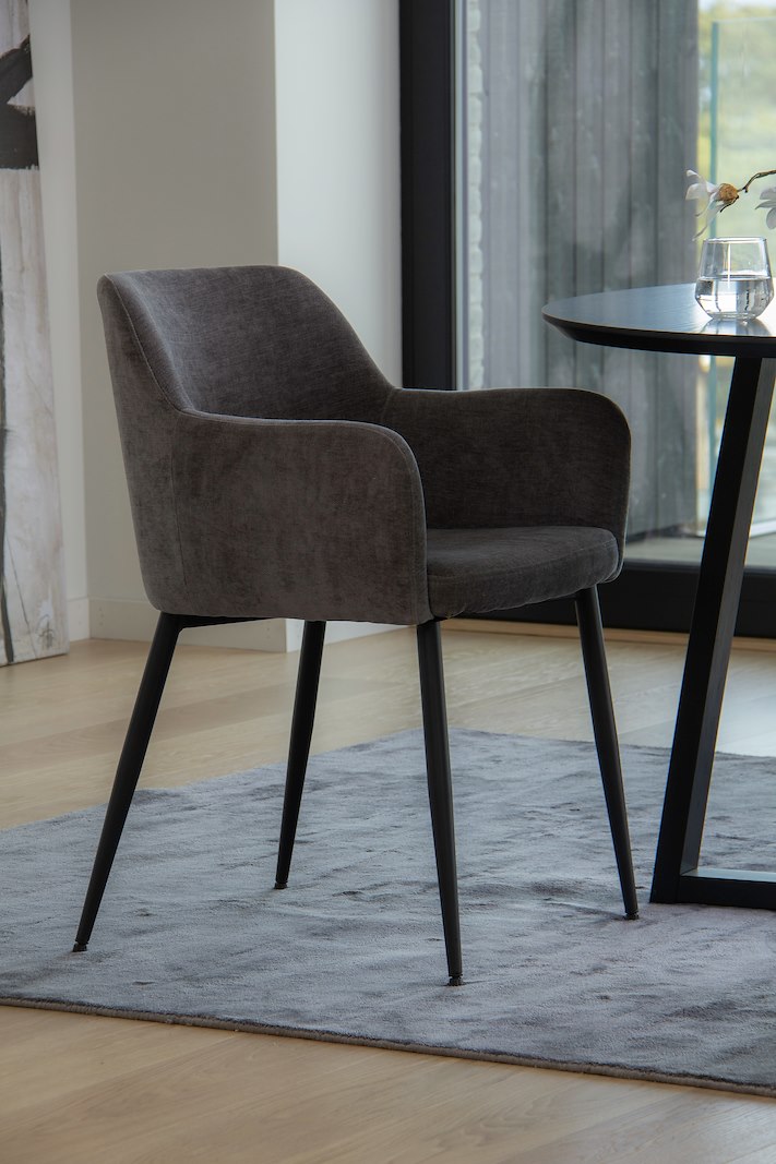 Karen spisestol I tekstil Dark grey. Med arm og matte sorte ben.