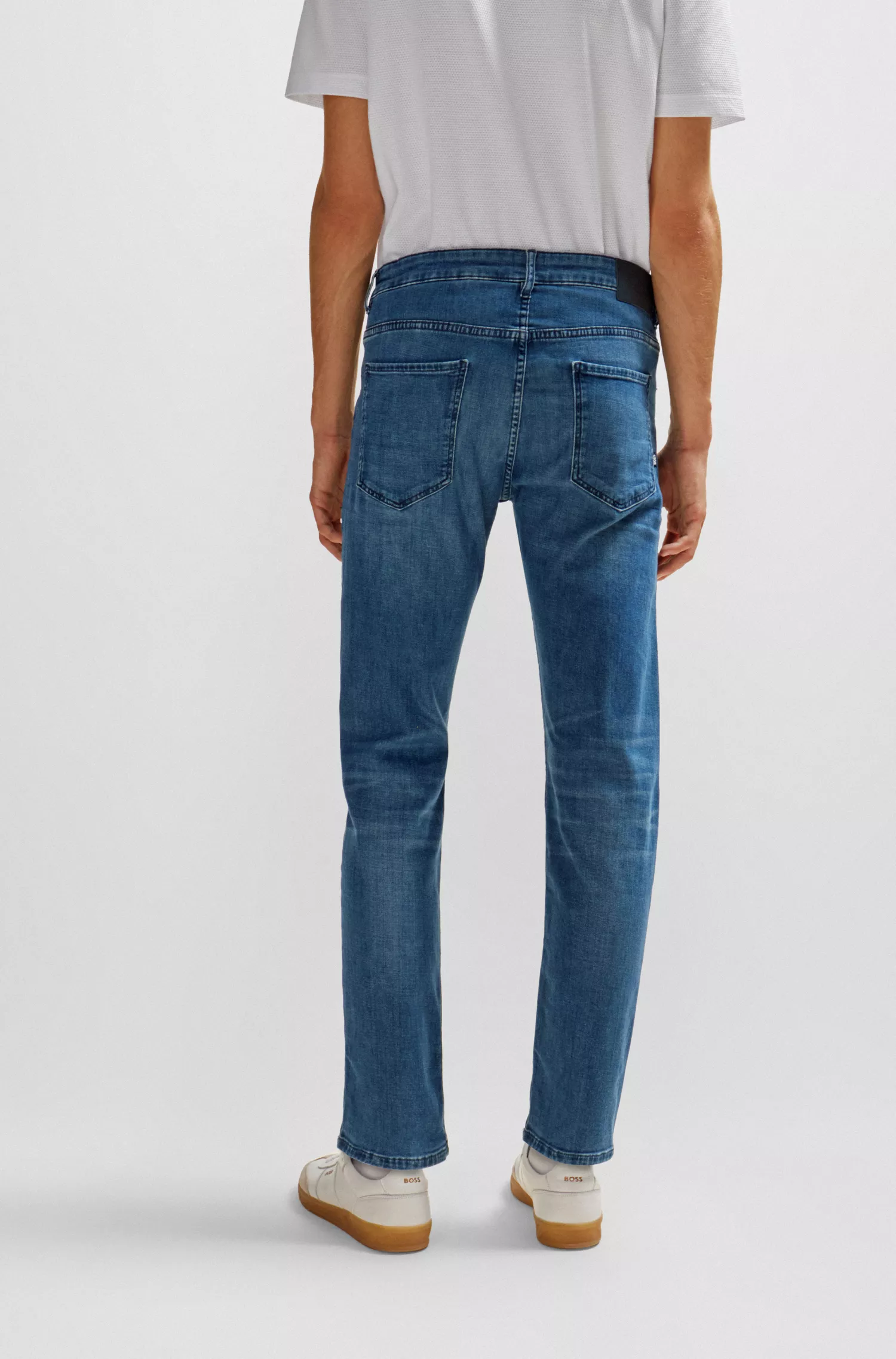 Calça jeans BOSS preta, corte afunilado, em denim elástico azul.