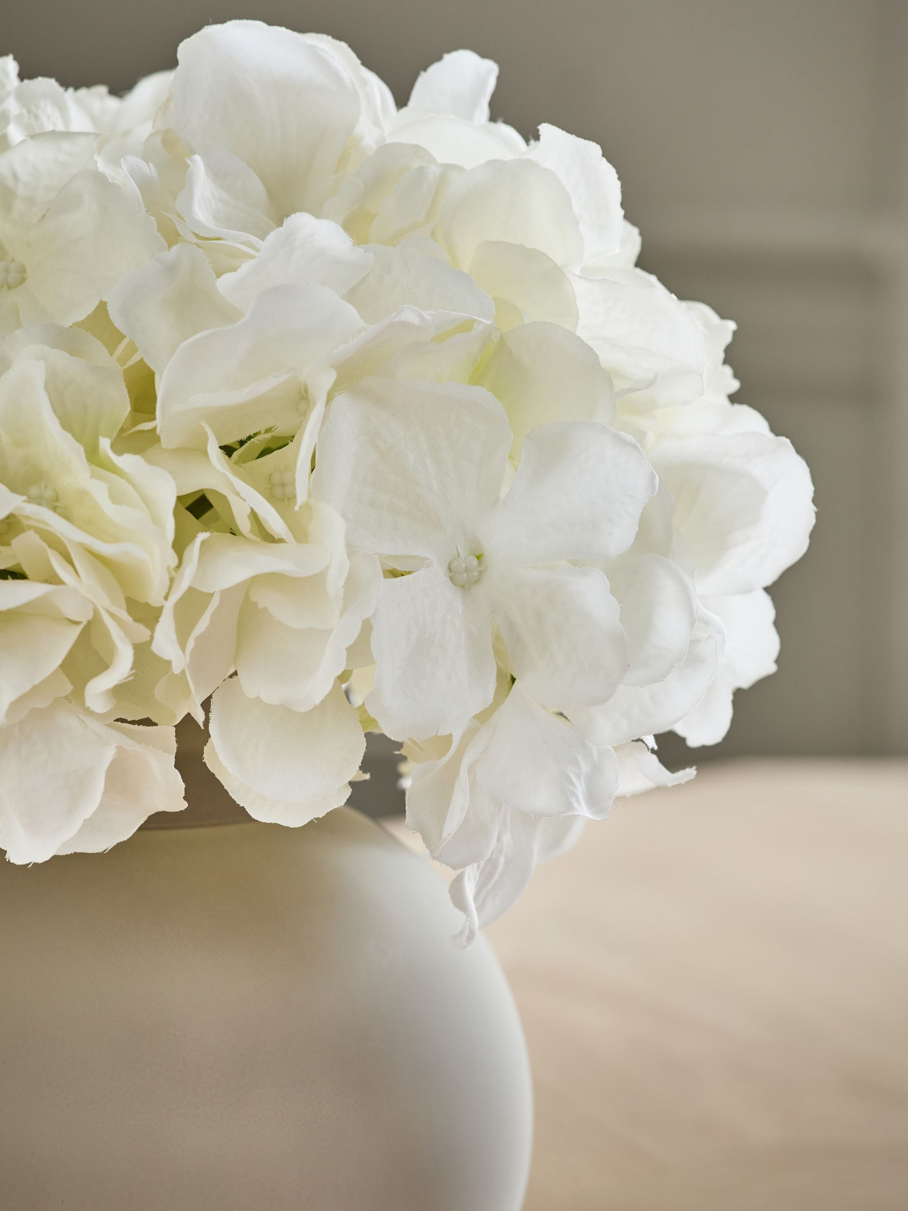 Arrangement met kunsthortensia in grote grijze glazen vaas
