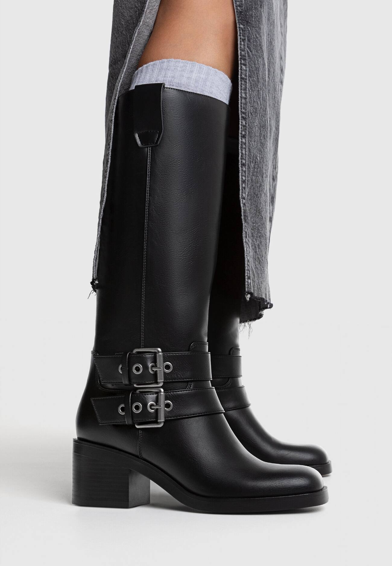 Botas pretas de motociclista com salto e fivelas.
