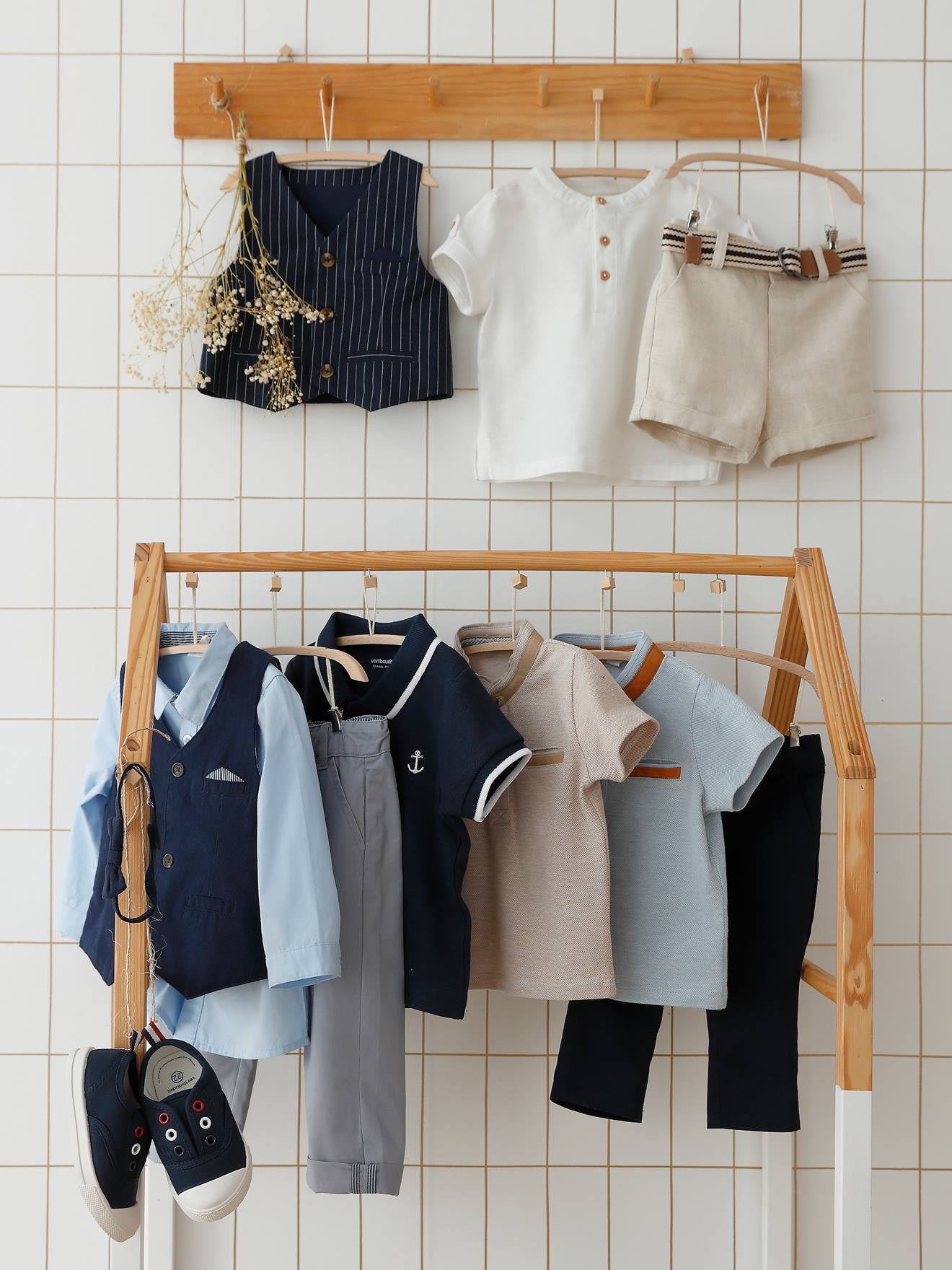 Conjunto formal para bebê menino com colete de tricô, camisa, gravata borboleta e calça azul-escura lisa.