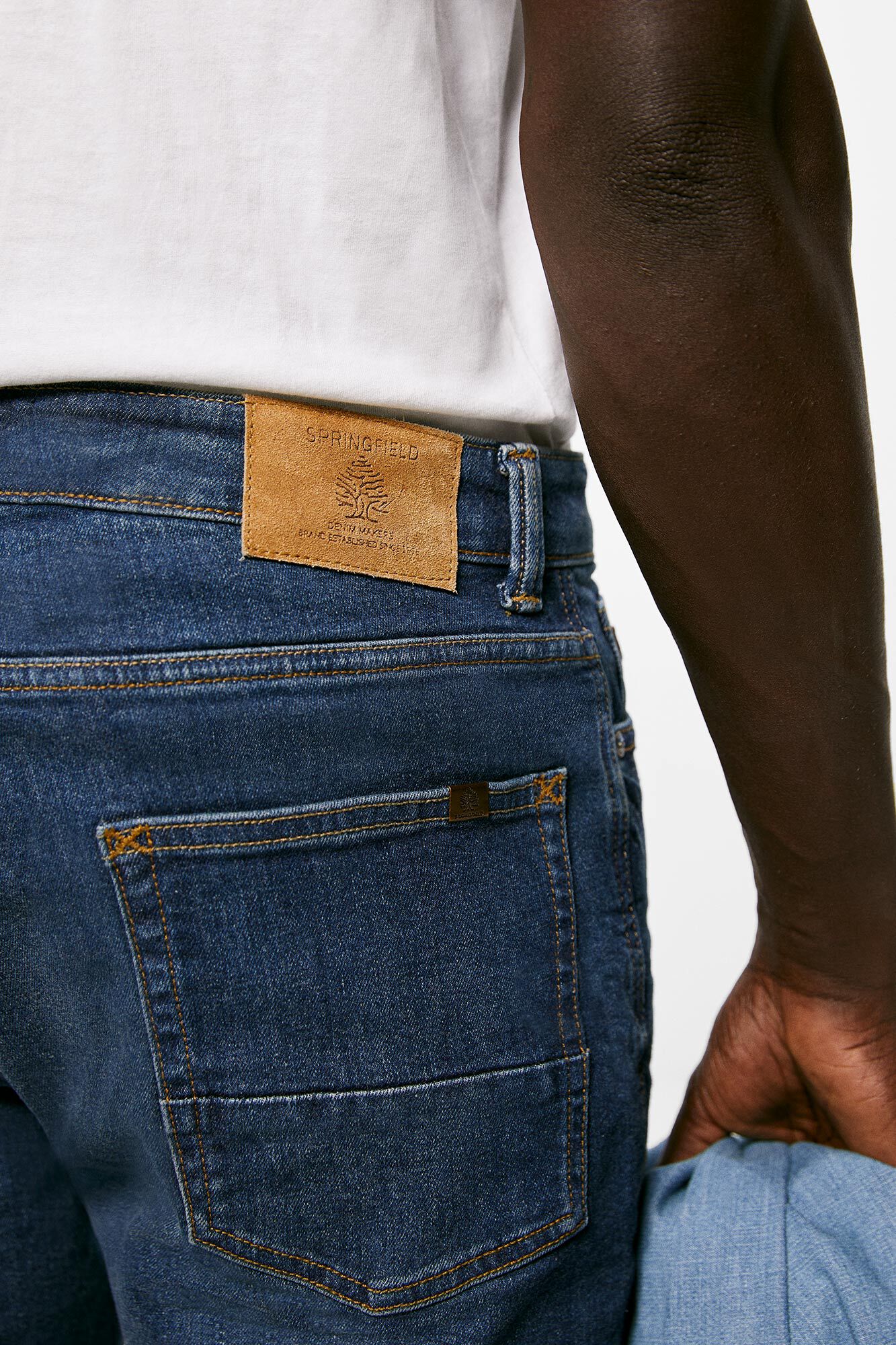 Calça jeans slim, lavagem clara escura, com detalhes desgastados.