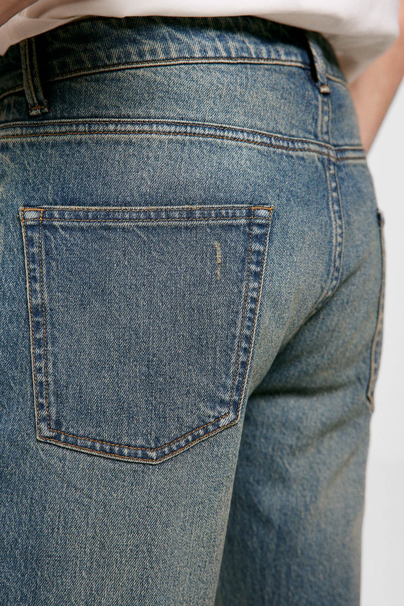 Calça jeans slim, lavagem média, levemente suja.