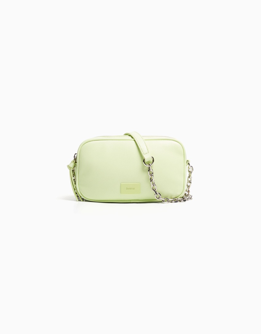 Bolsa transversal com fecho duplo de zíper e corrente.