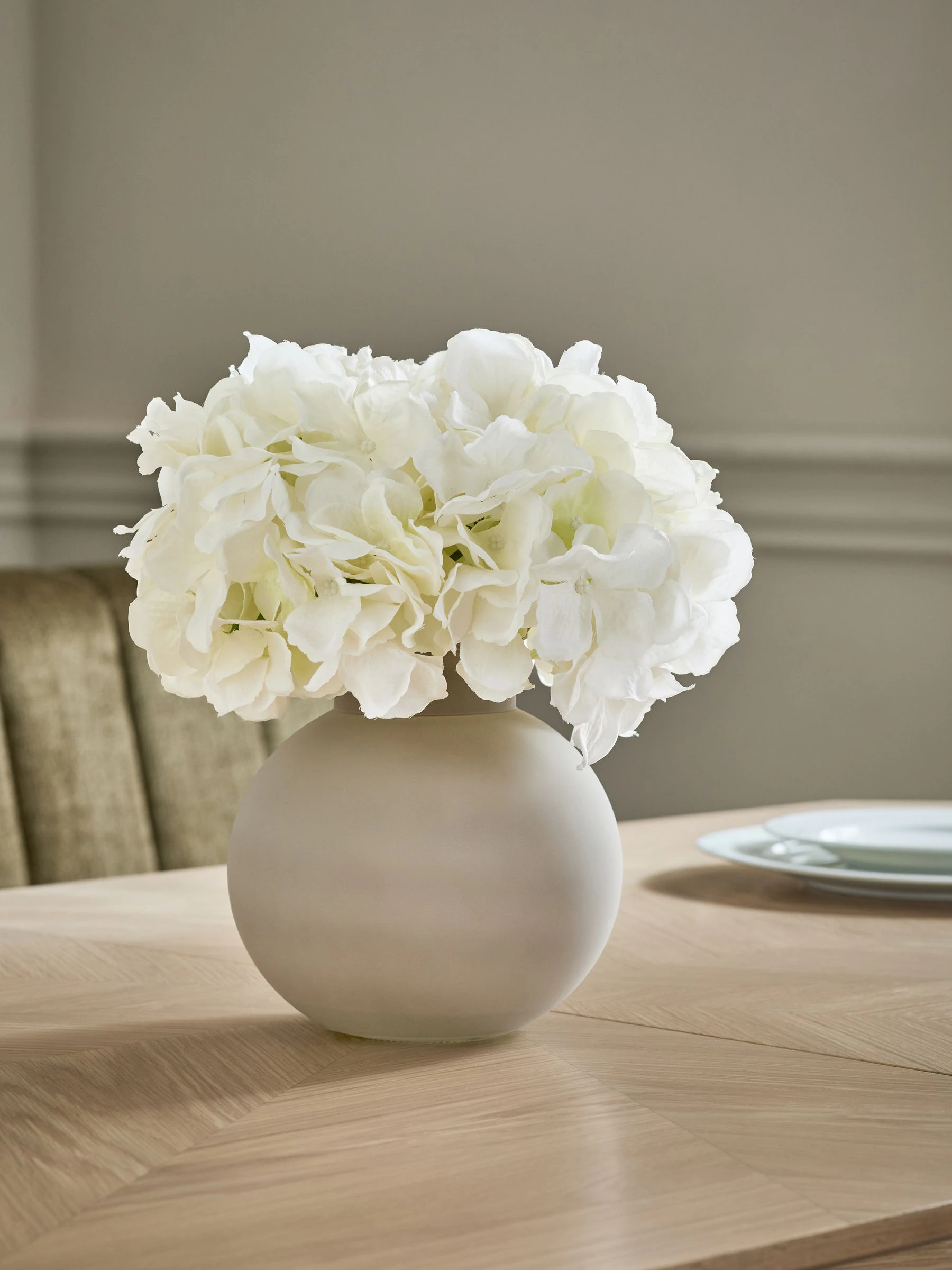 Arrangement met kunsthortensia in grote grijze glazen vaas
