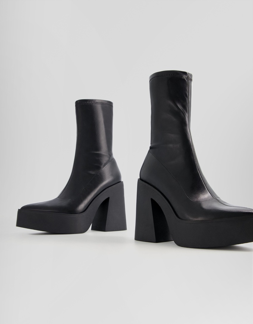 Botas de cano curto com plataforma e salto alto e bico fino.