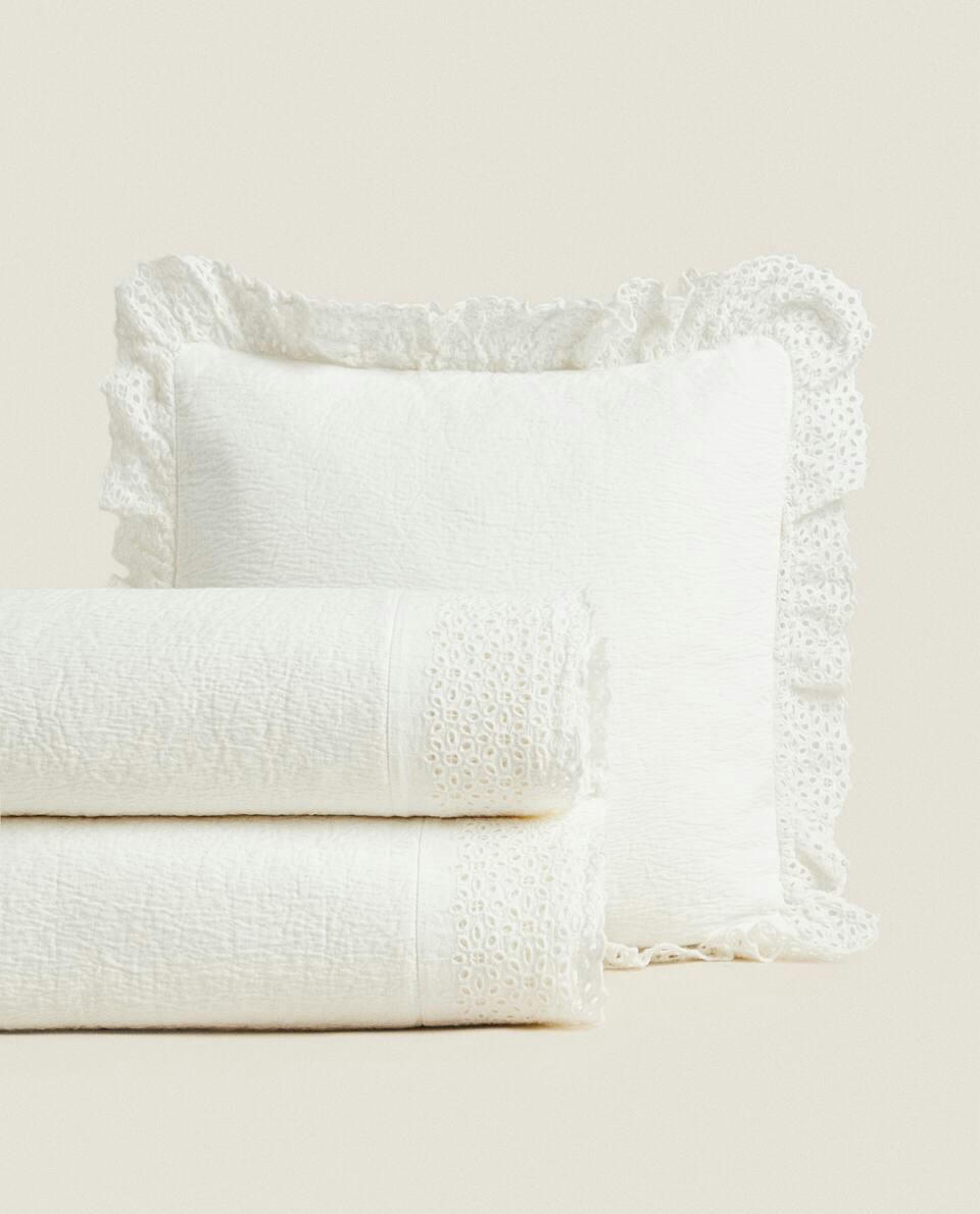 Colcha de algodão com detalhes bordados e franzidos.