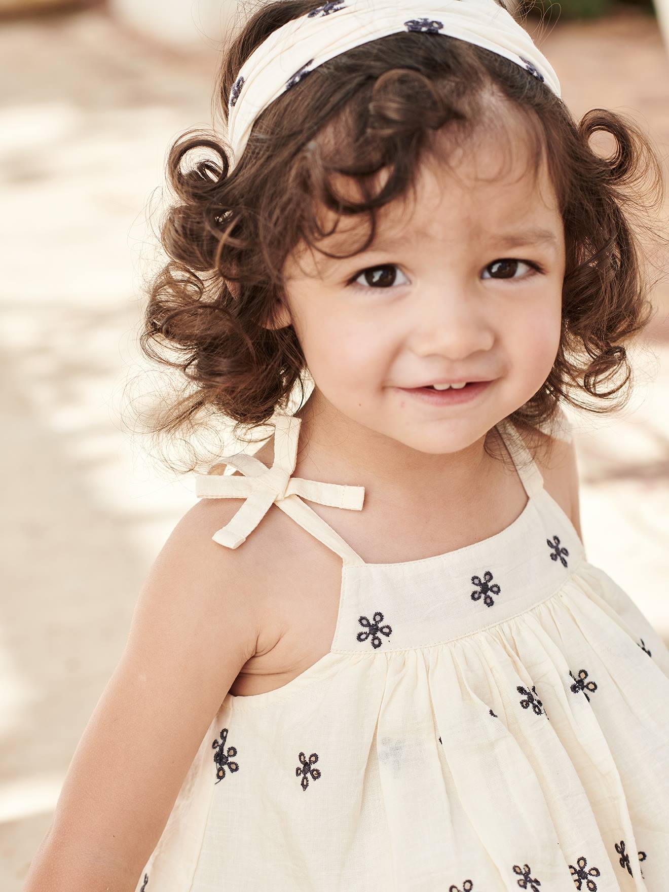 Conjunto para bebê: vestido bordado, calcinha tipo bloomer e faixa de cabelo bege combinando.