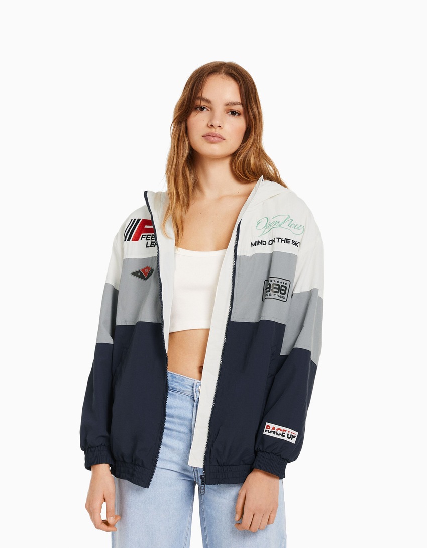Jaqueta de nylon com capuz e patches.