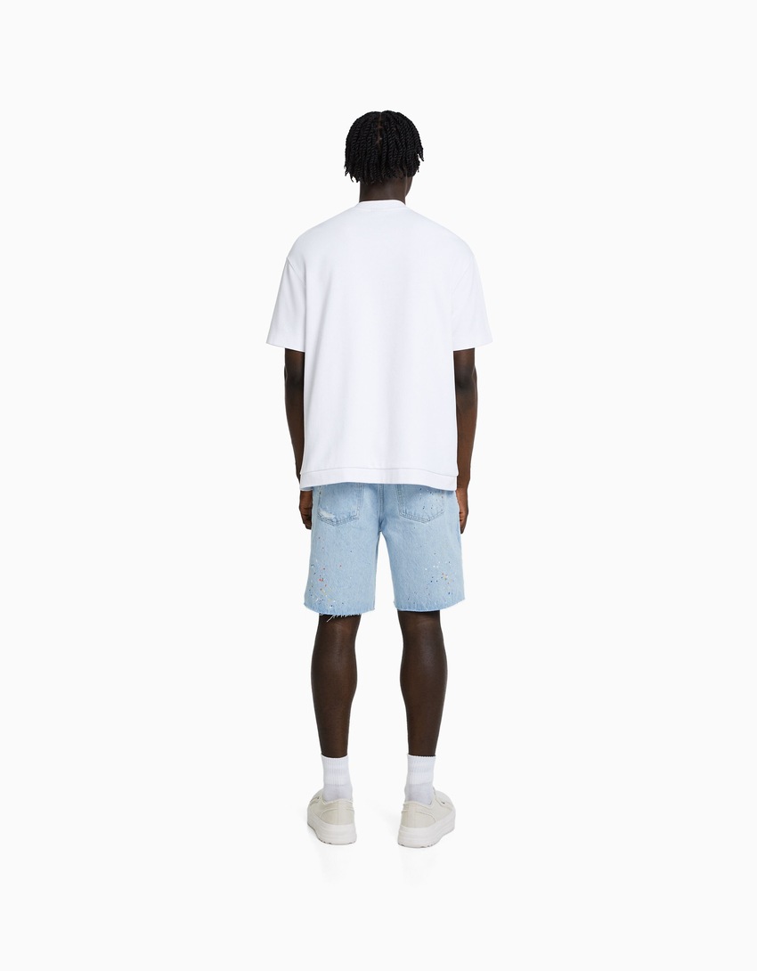 Bermuda jeans rasgada com respingos de tinta