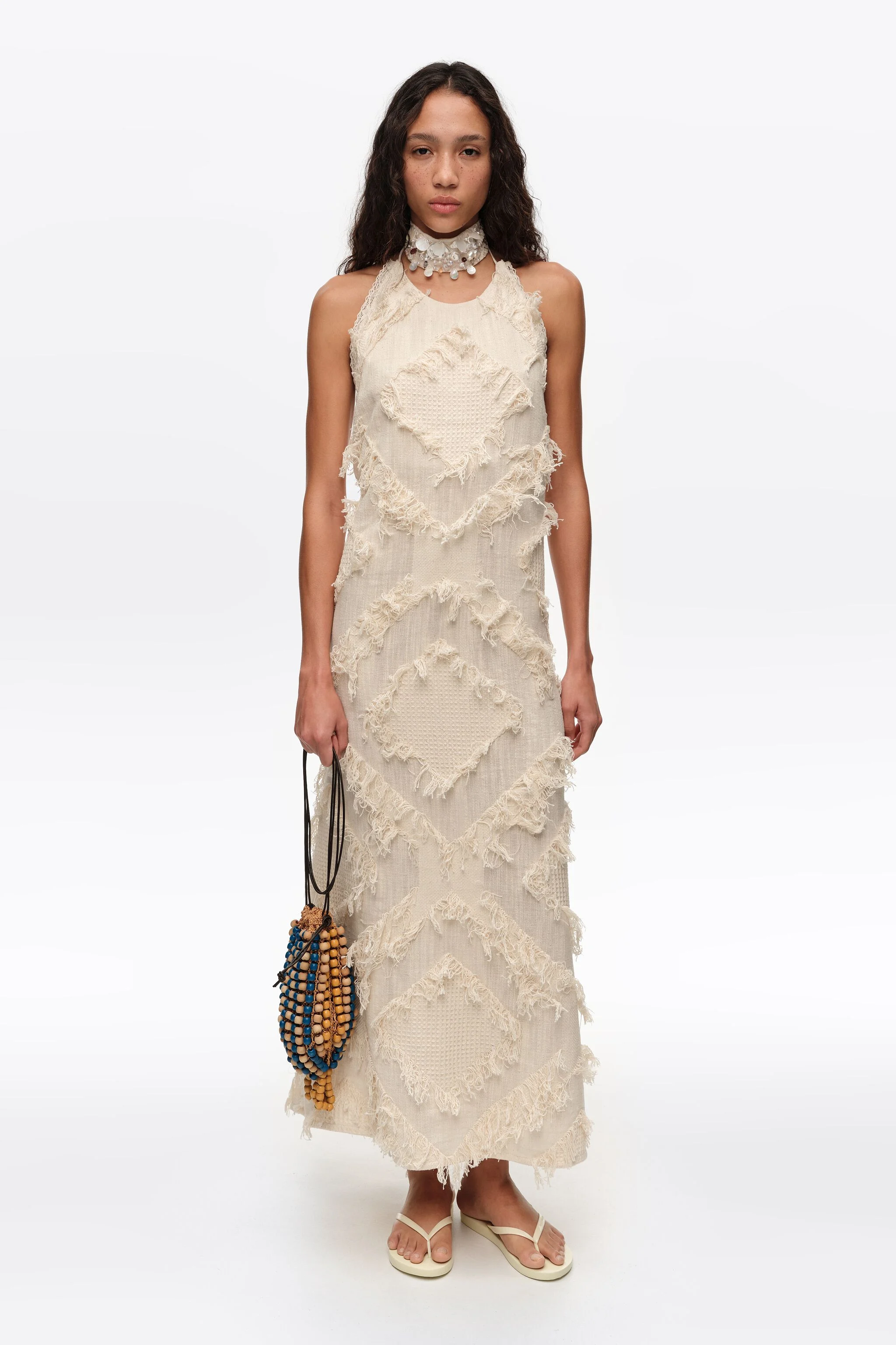 Vestido marfim com decote halter e franjas.