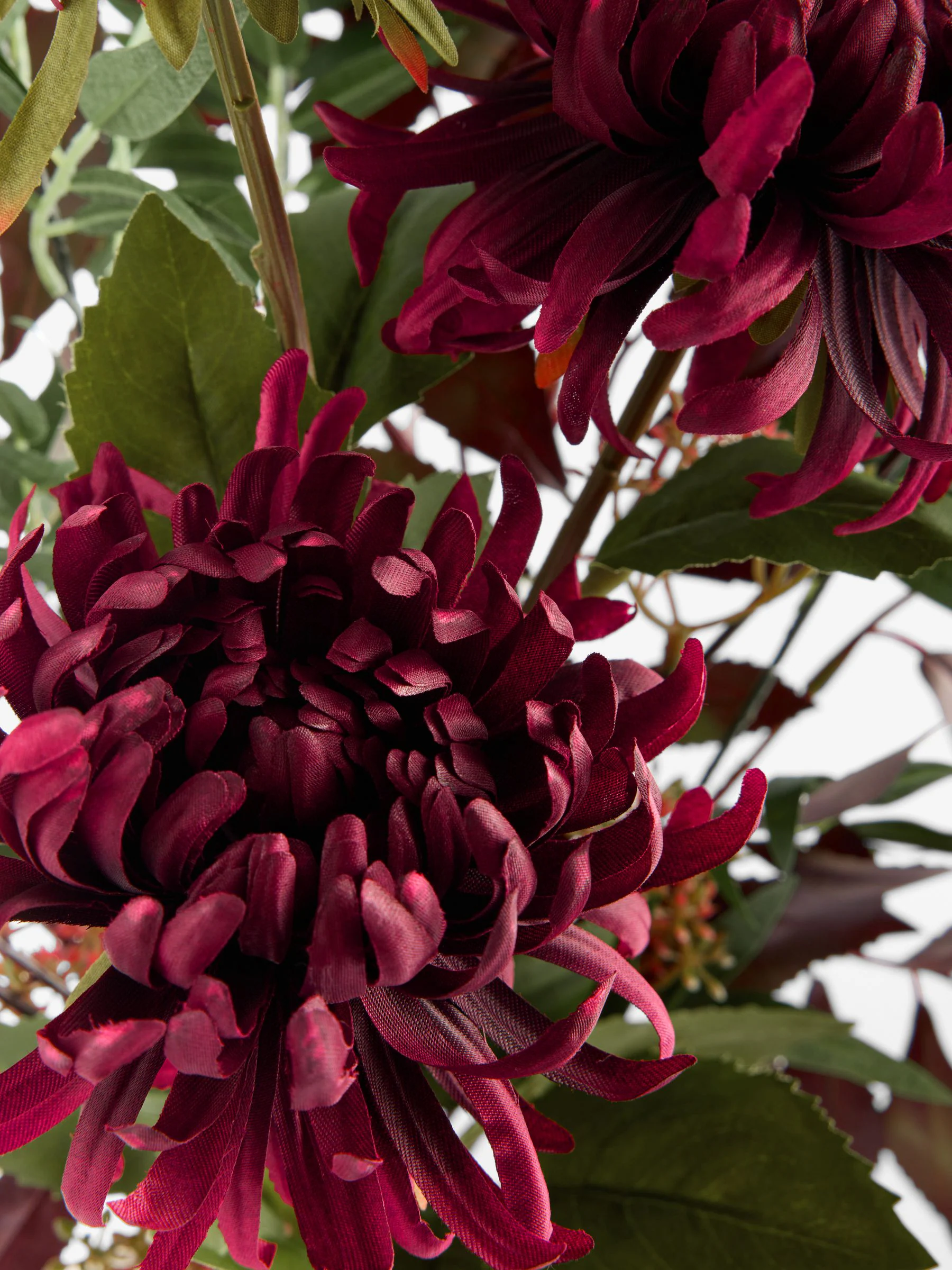 Kunstbloemstuk met donkere bloemen in keramische vaas