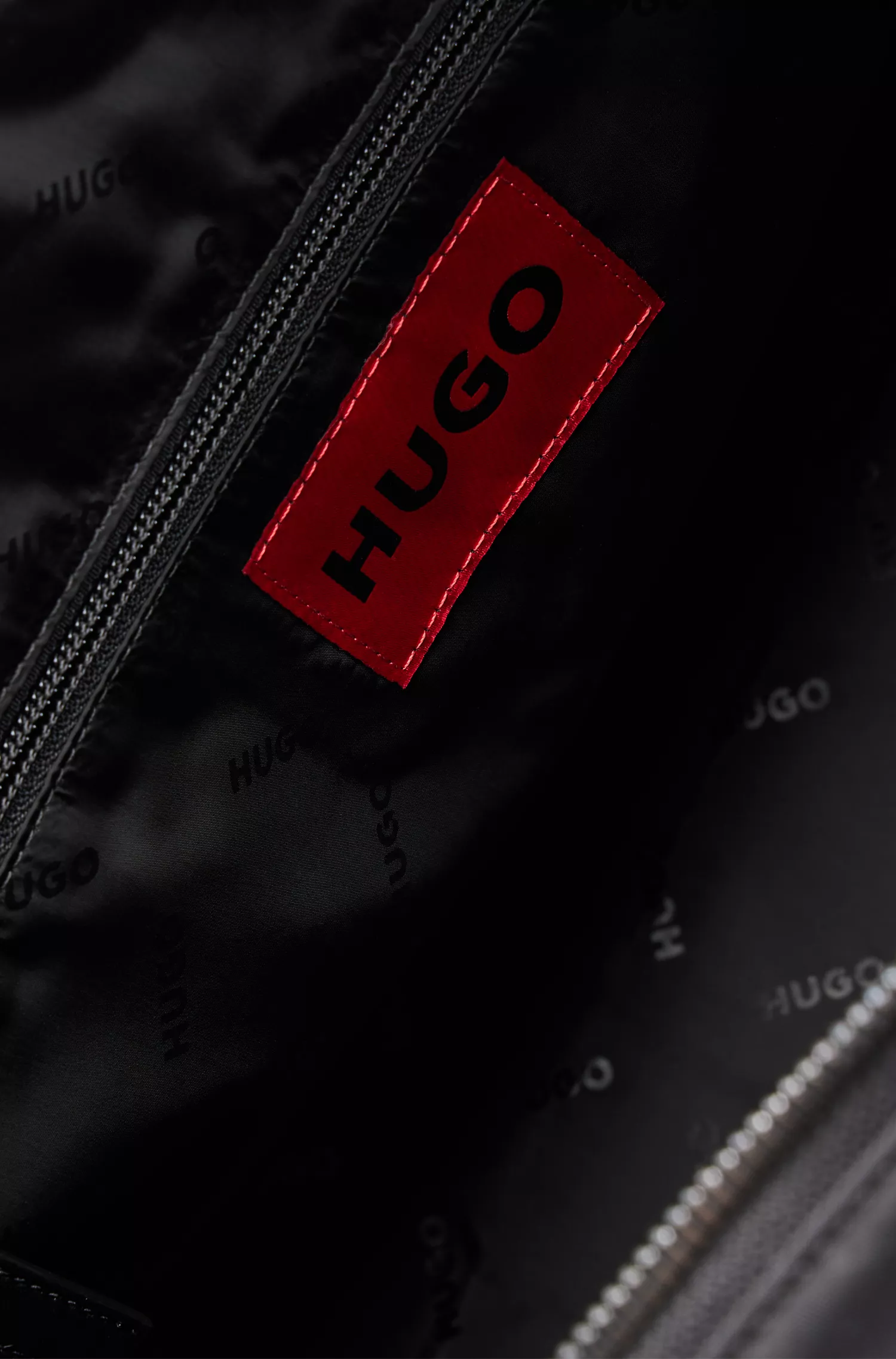 Mala de viagem HUGO com detalhes em vermelho e alças personalizadas.