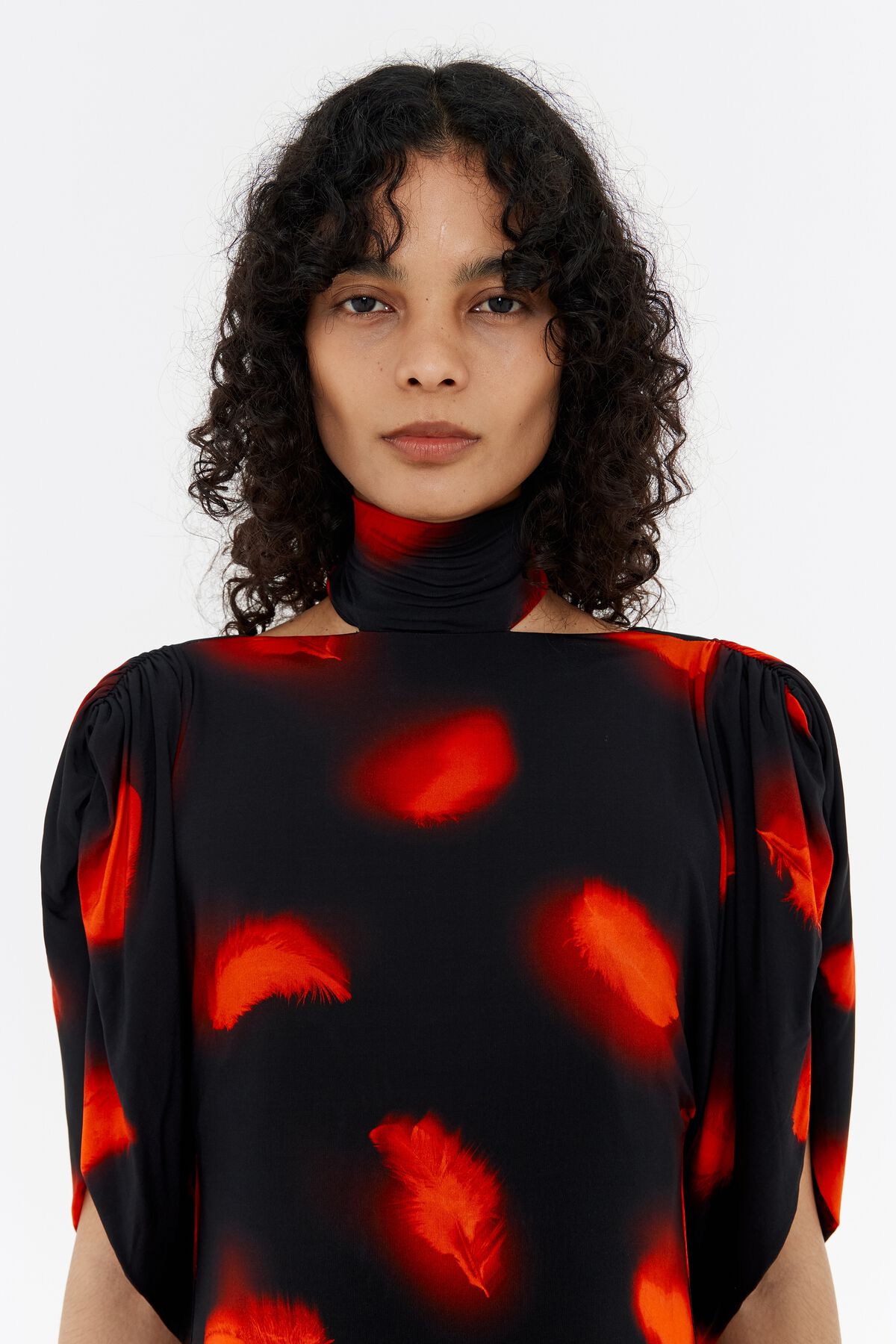 Vestido curto vermelho com ombros à mostra e penas