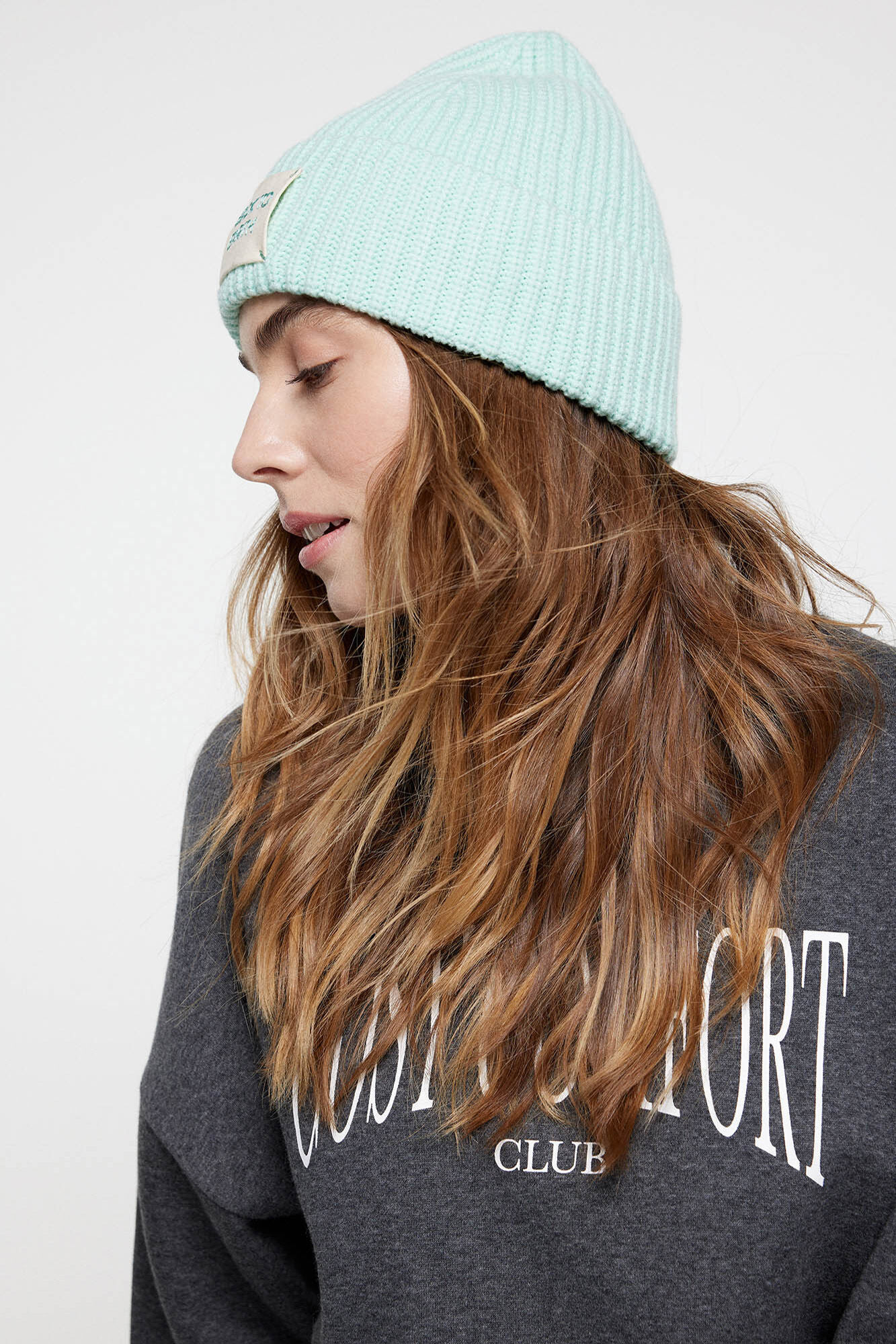 Gorro de malha macia com aba enrolada e detalhe com a inscrição 