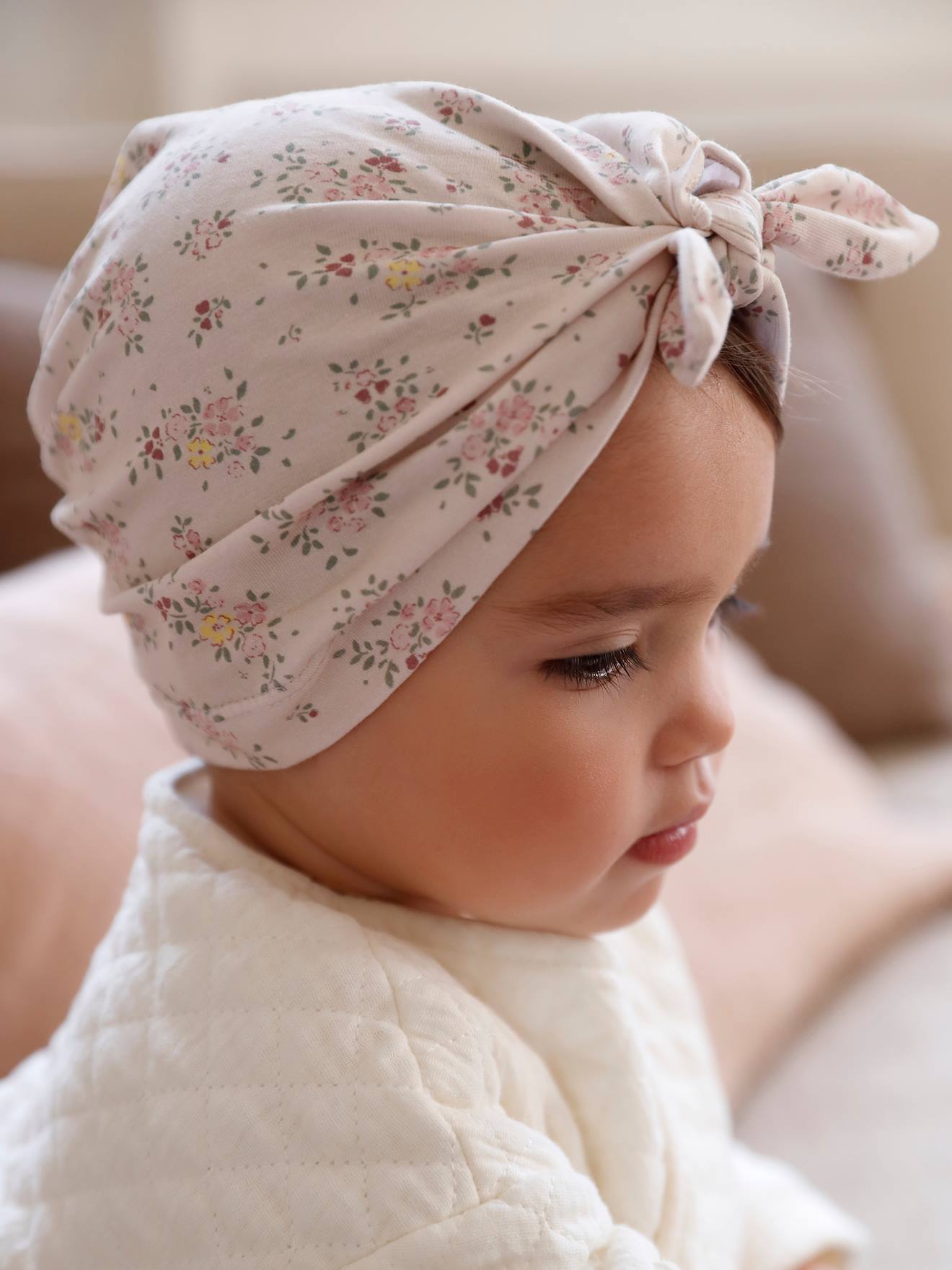 Touca infantil bege de tricô estilo turbante com estampa.