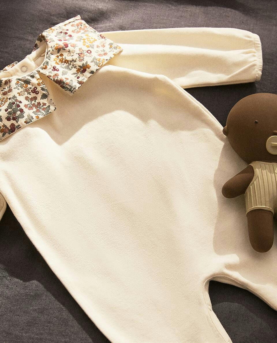 Macacão infantil em tecido com estampa floral e detalhe de gola.