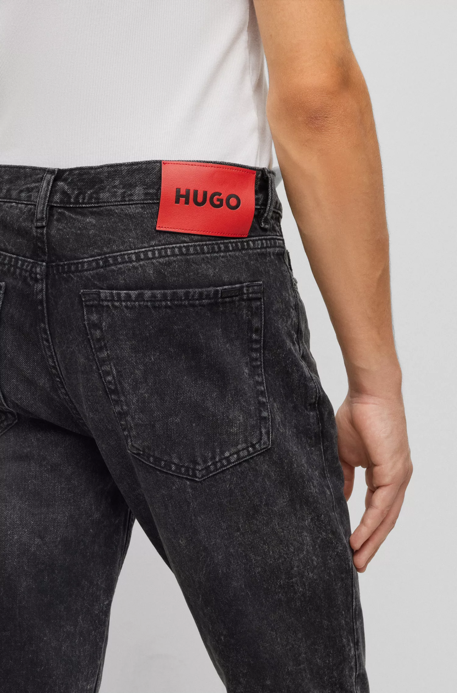 Calça jeans HUGO vermelha, corte afunilado, em denim rígido preto.