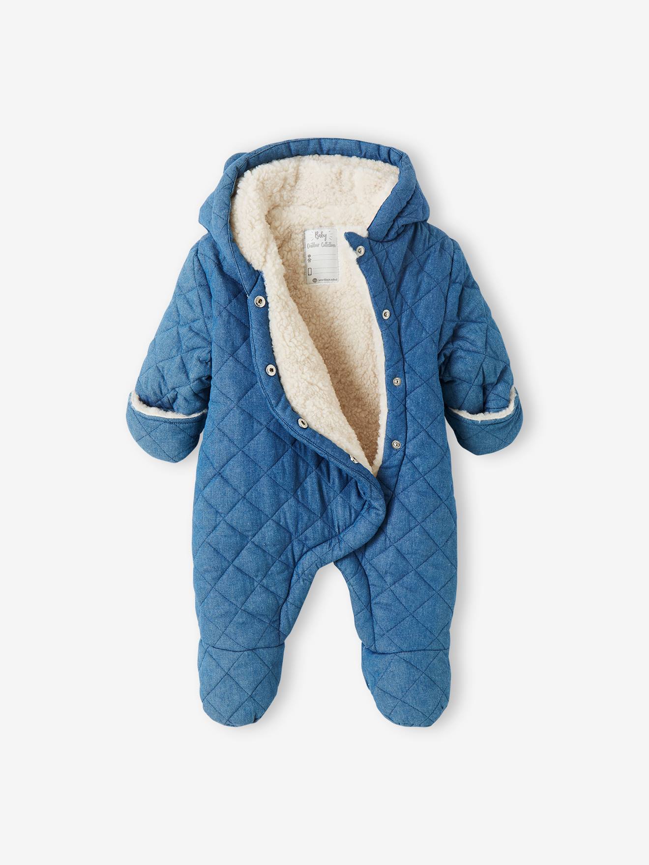 Macacão jeans chambray azul médio para bebê menina, estilo piloto, com abertura assimétrica.