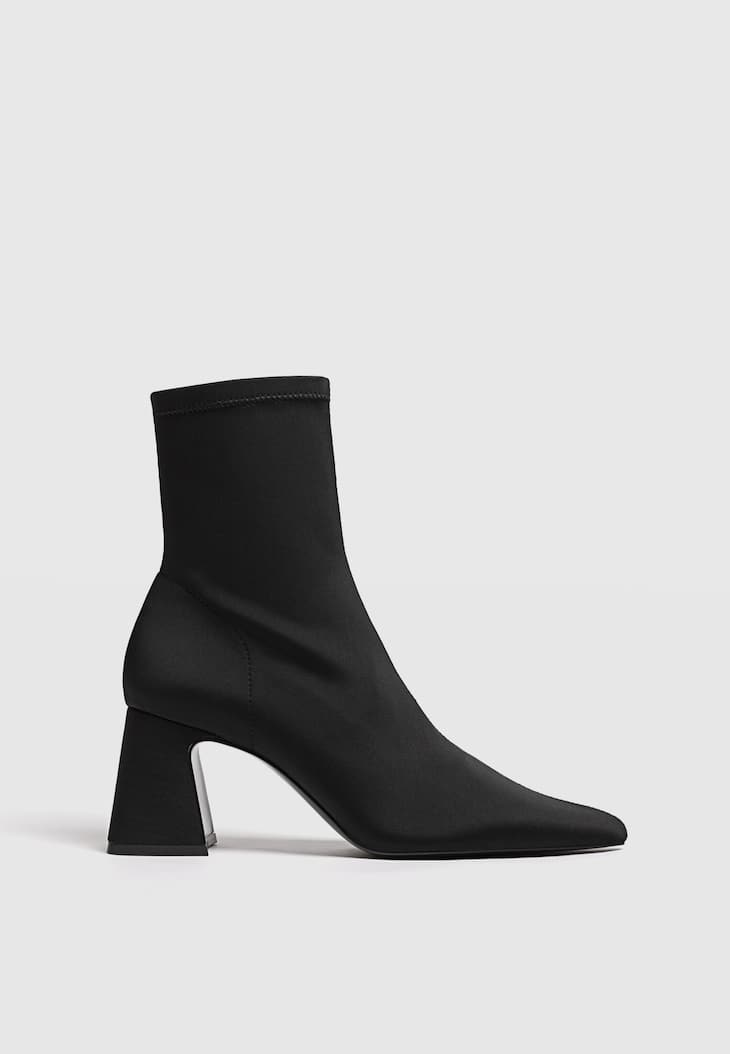 Botas pretas de cano curto com salto alto e cano curto, em tecido elástico.