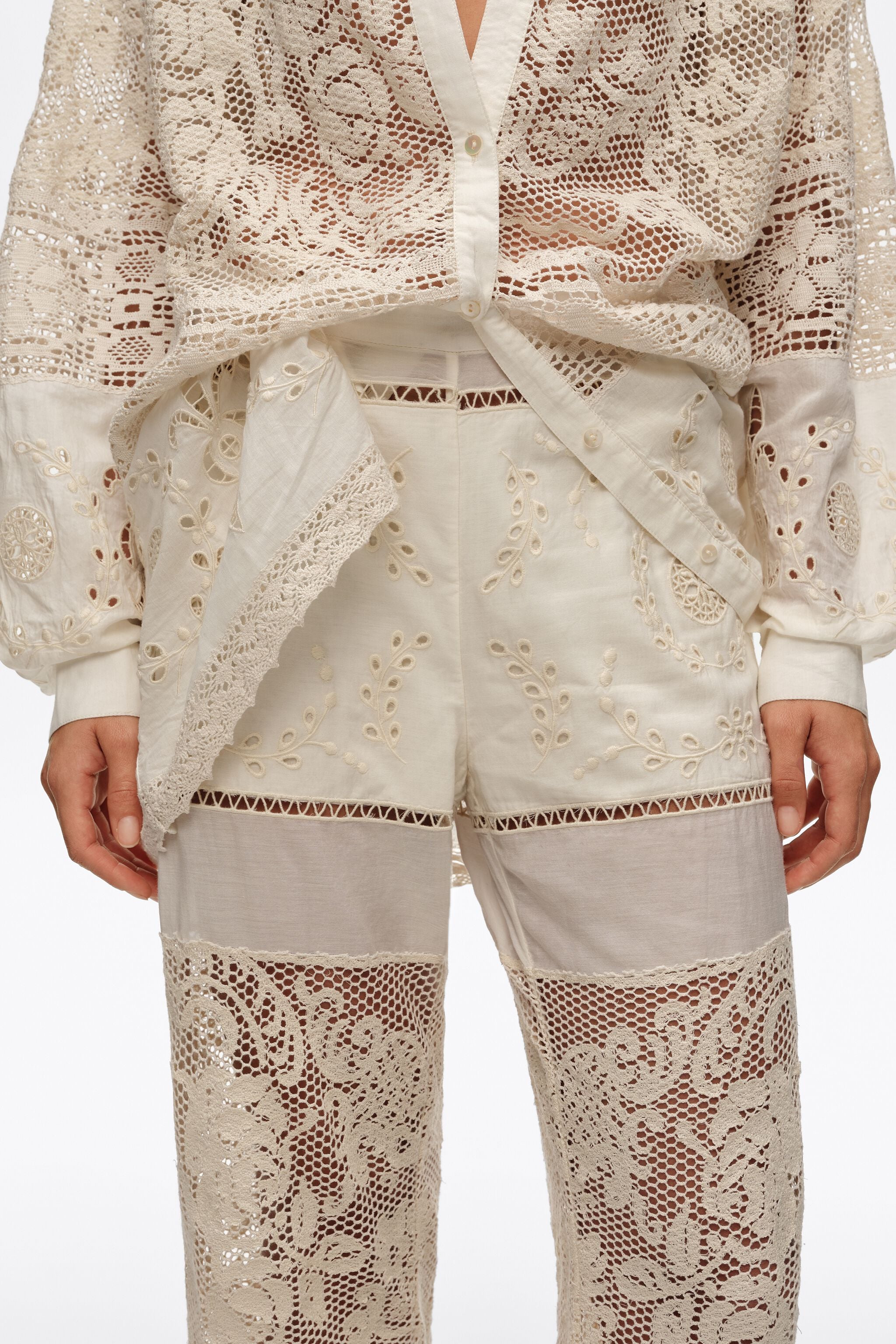 Calças cor creme com bordados e detalhes vazados.