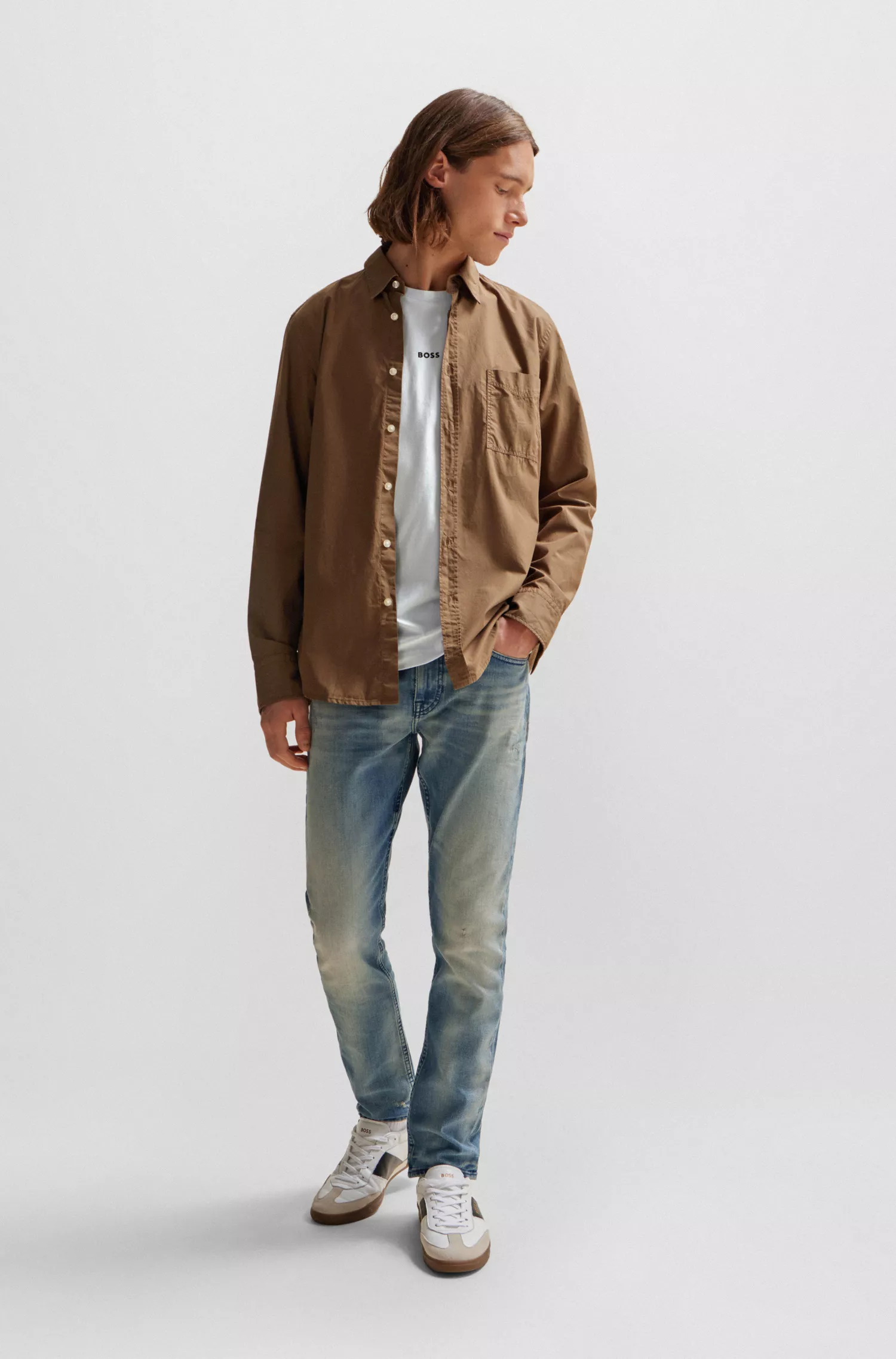 Calça jeans BOSS laranja, corte slim, em denim azul com tonalidade bege.