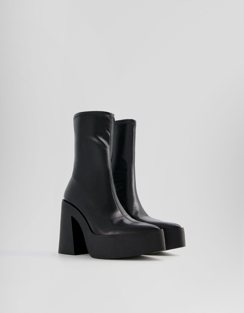 Botas de cano curto com plataforma e salto alto e bico fino.