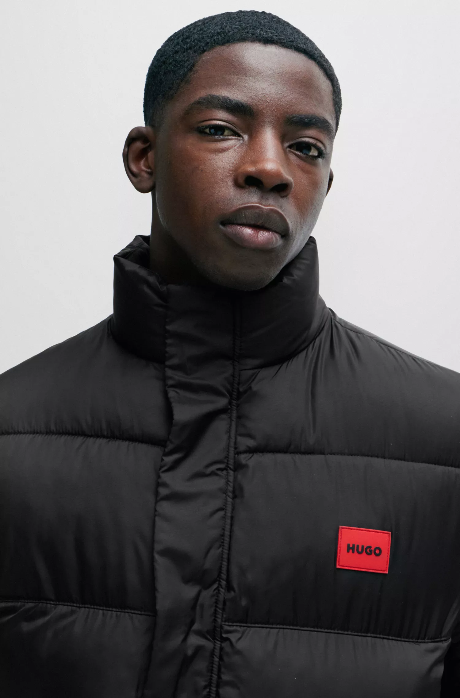 Jaqueta puffer HUGO vermelha, impermeável, com emblema vermelho da marca.