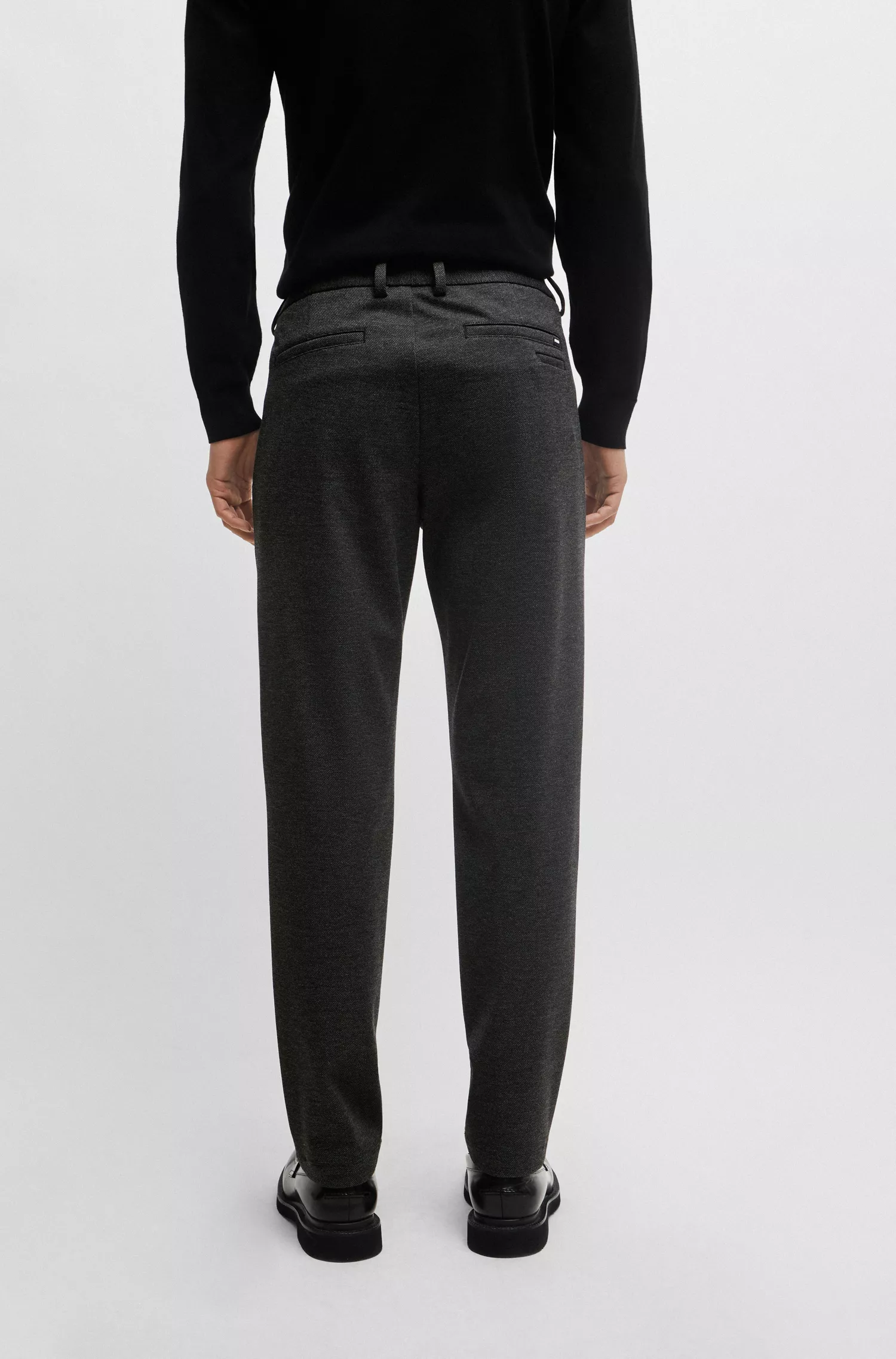 Calça BOSS preta, corte slim, em tecido estruturado de alta performance com elasticidade.