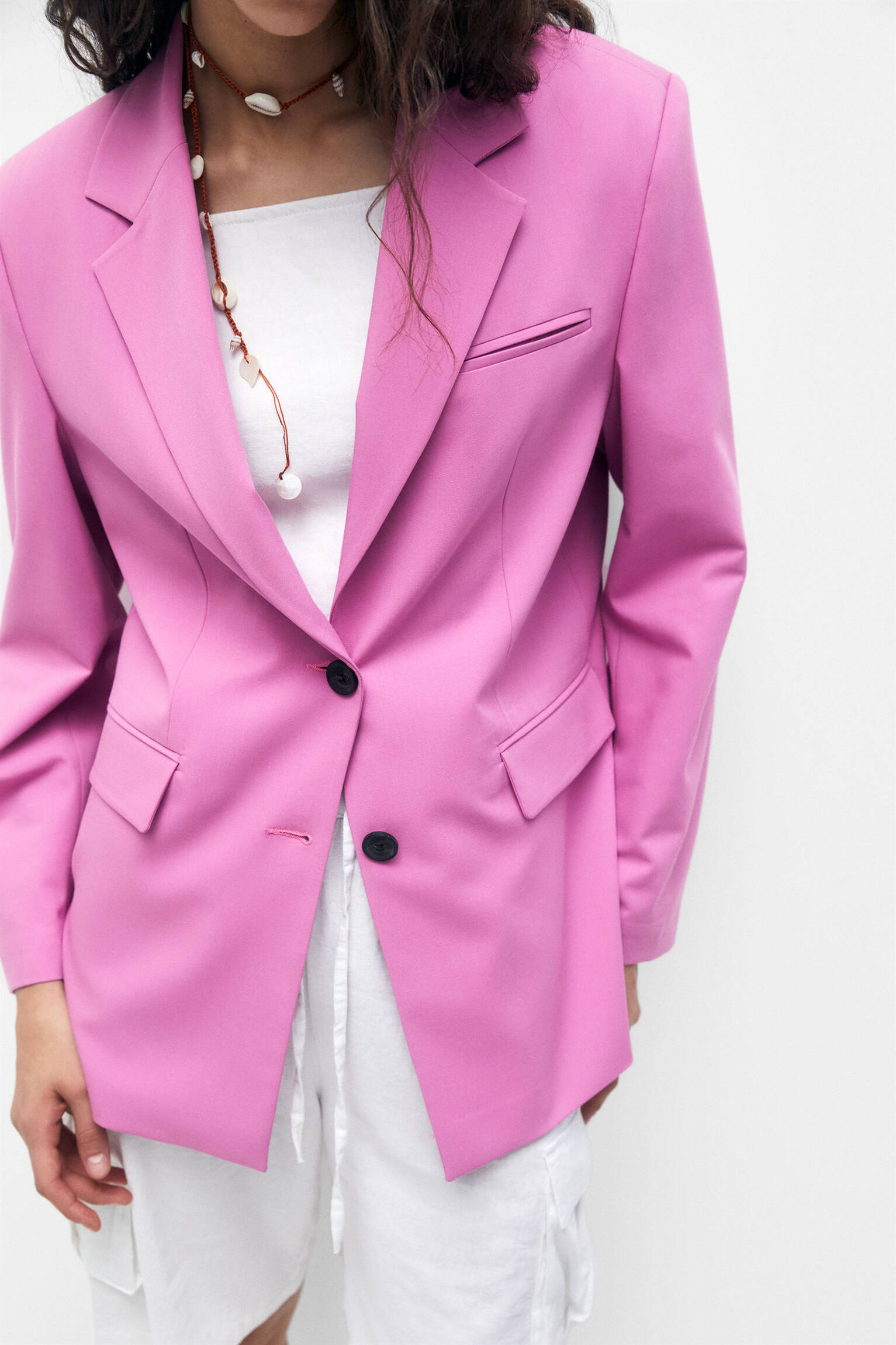Blazer rosa com abotoamento duplo e detalhe na foto.
