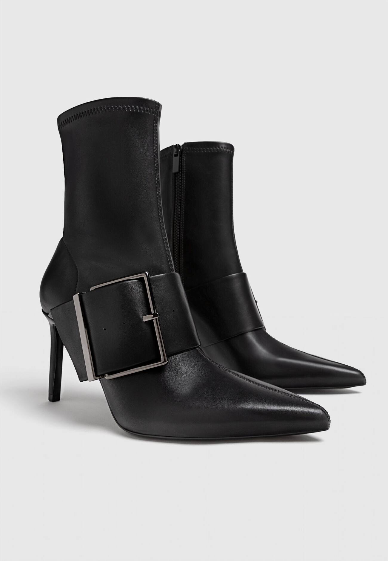 Botas pretas de cano curto com salto alto e fivelas.