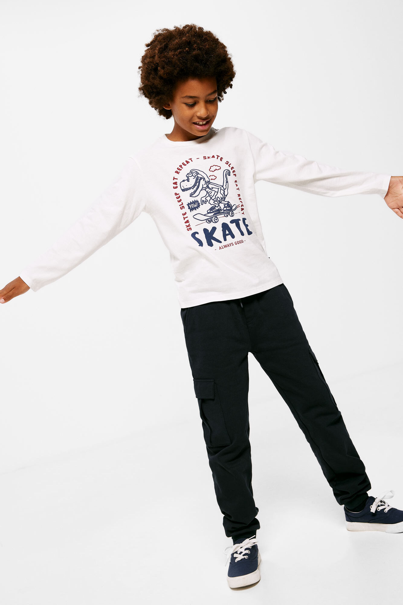 Camiseta infantil com estampa de dinossauro e skatista.