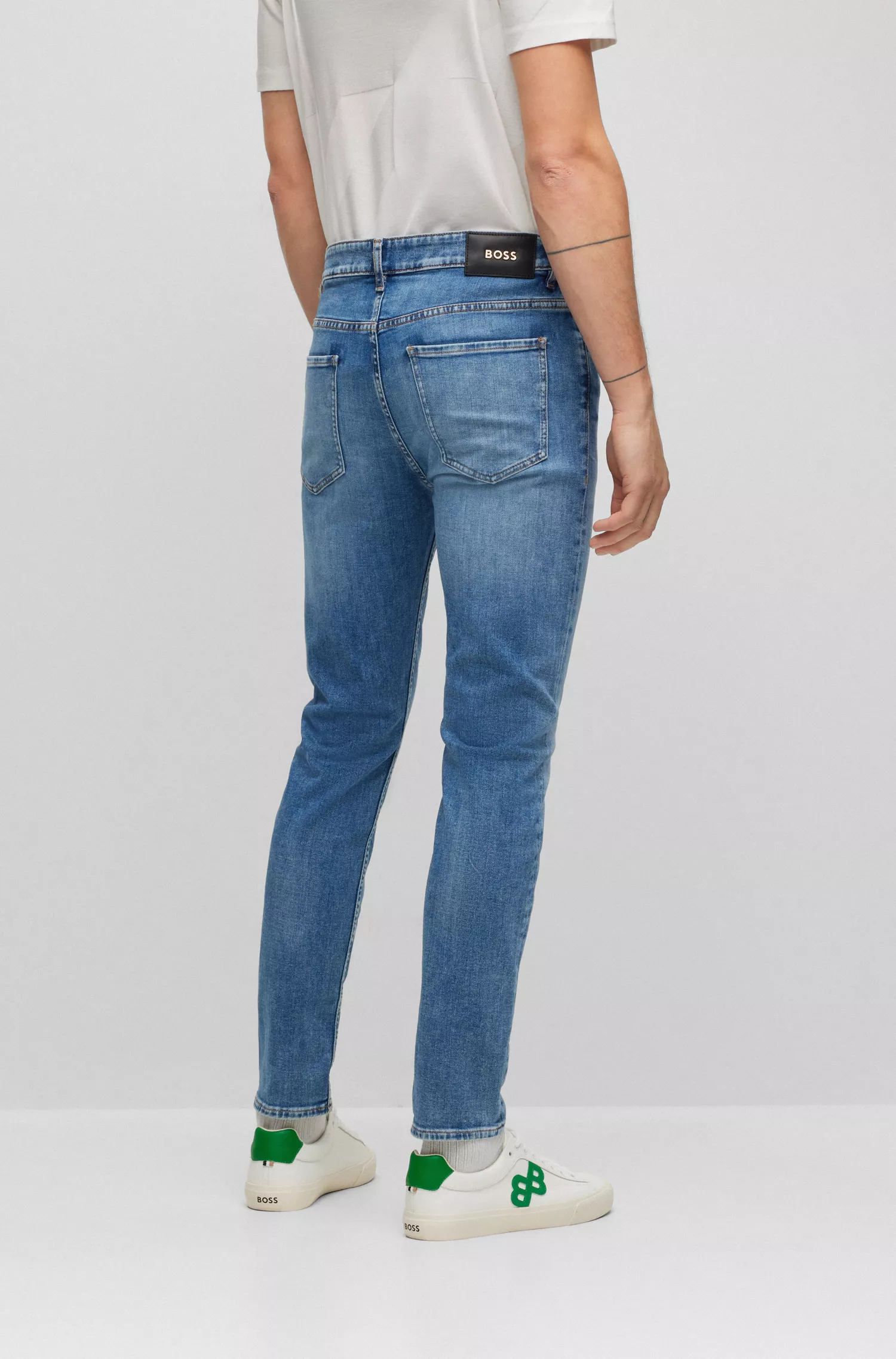 Calça jeans BOSS preta, corte afunilado, em denim italiano stretch azul médio.