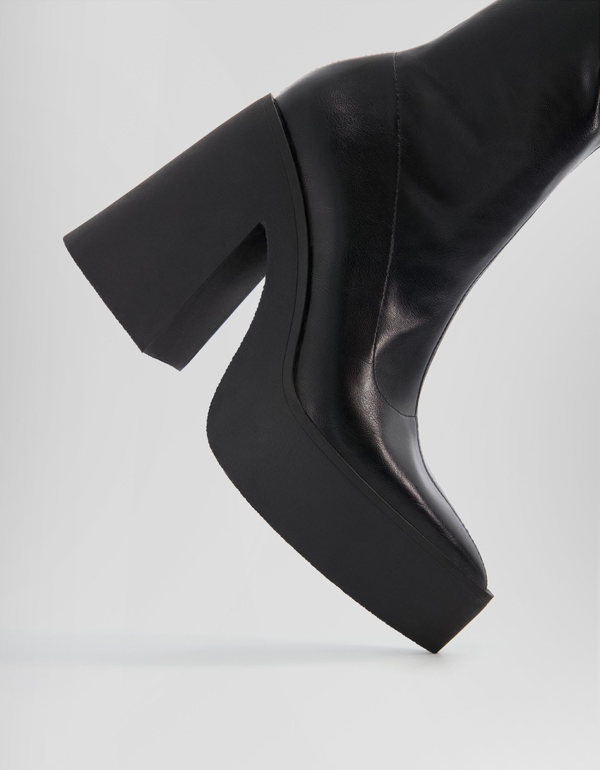 Botas de cano curto com plataforma e salto alto e bico fino.