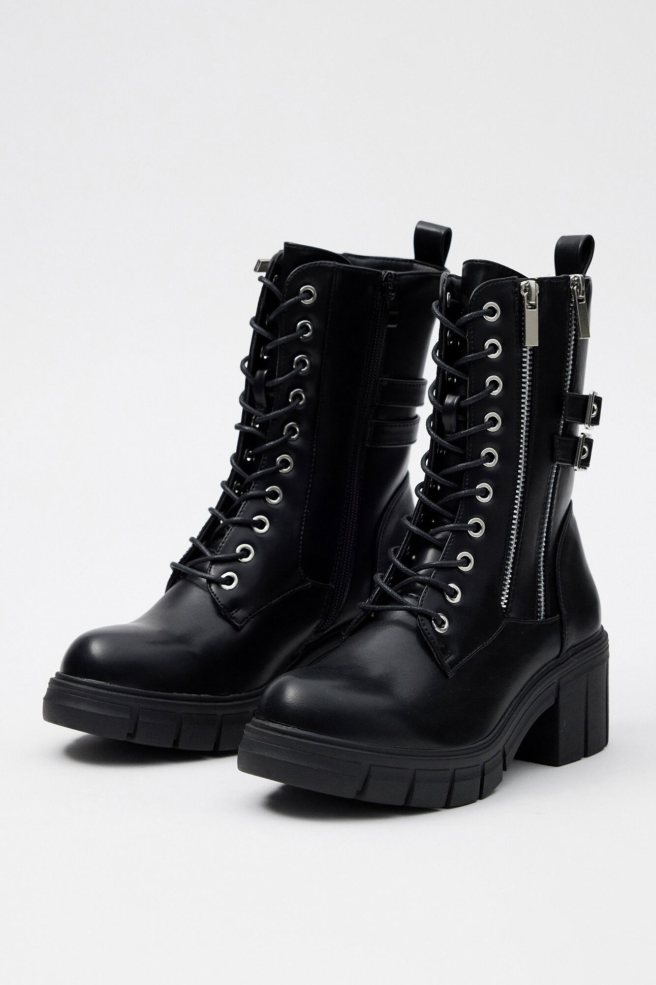 Bota de cano curto com fivelas, tachas e zíper.